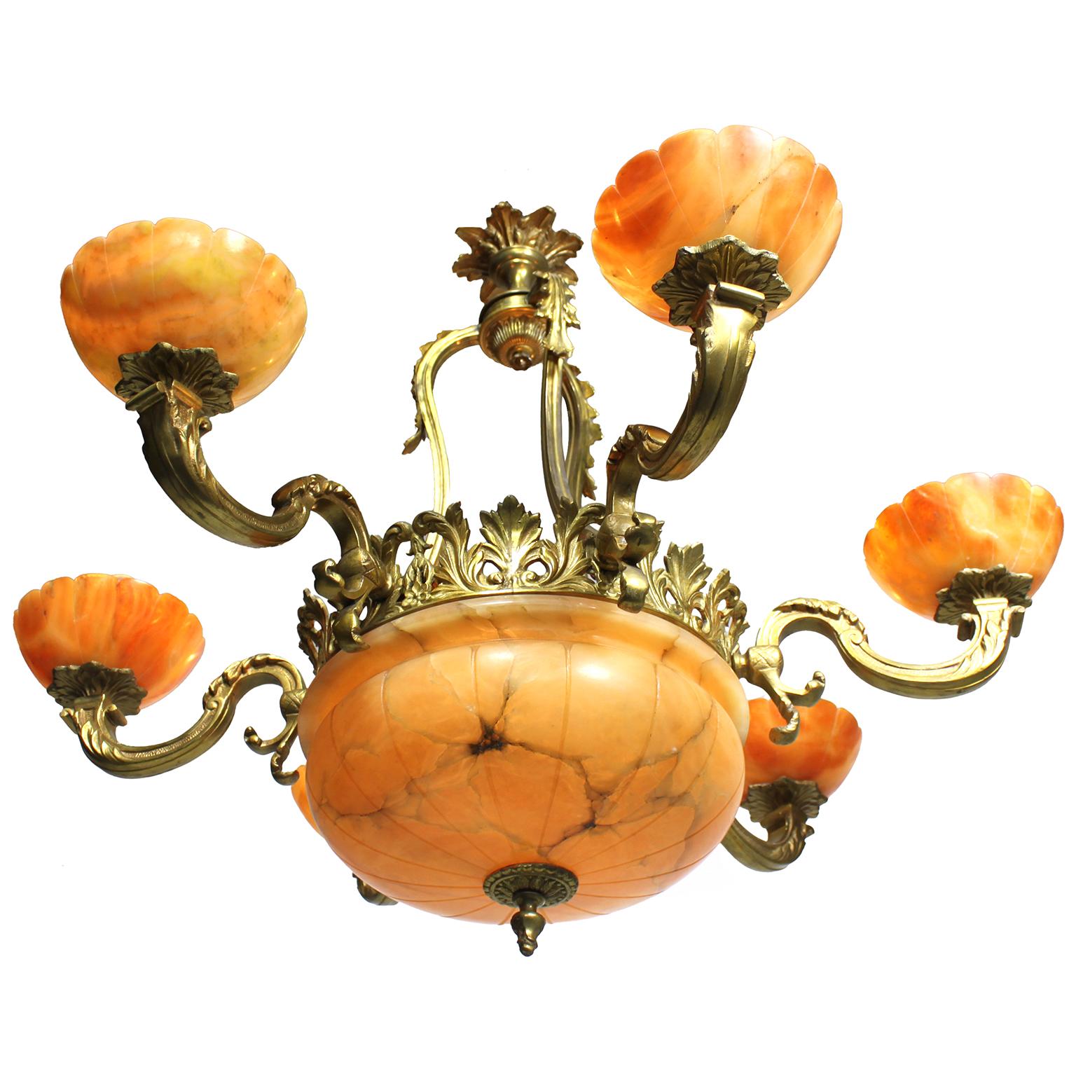 Lampadario a sei luci in bronzo e alabastro venato intagliato francese dei primi del Novecento. La cornice circolare argentata è sospesa da tre bretelle a volute con decorazioni ad acanto, con sei luci a braccio sagomate a volute, tutte dotate di