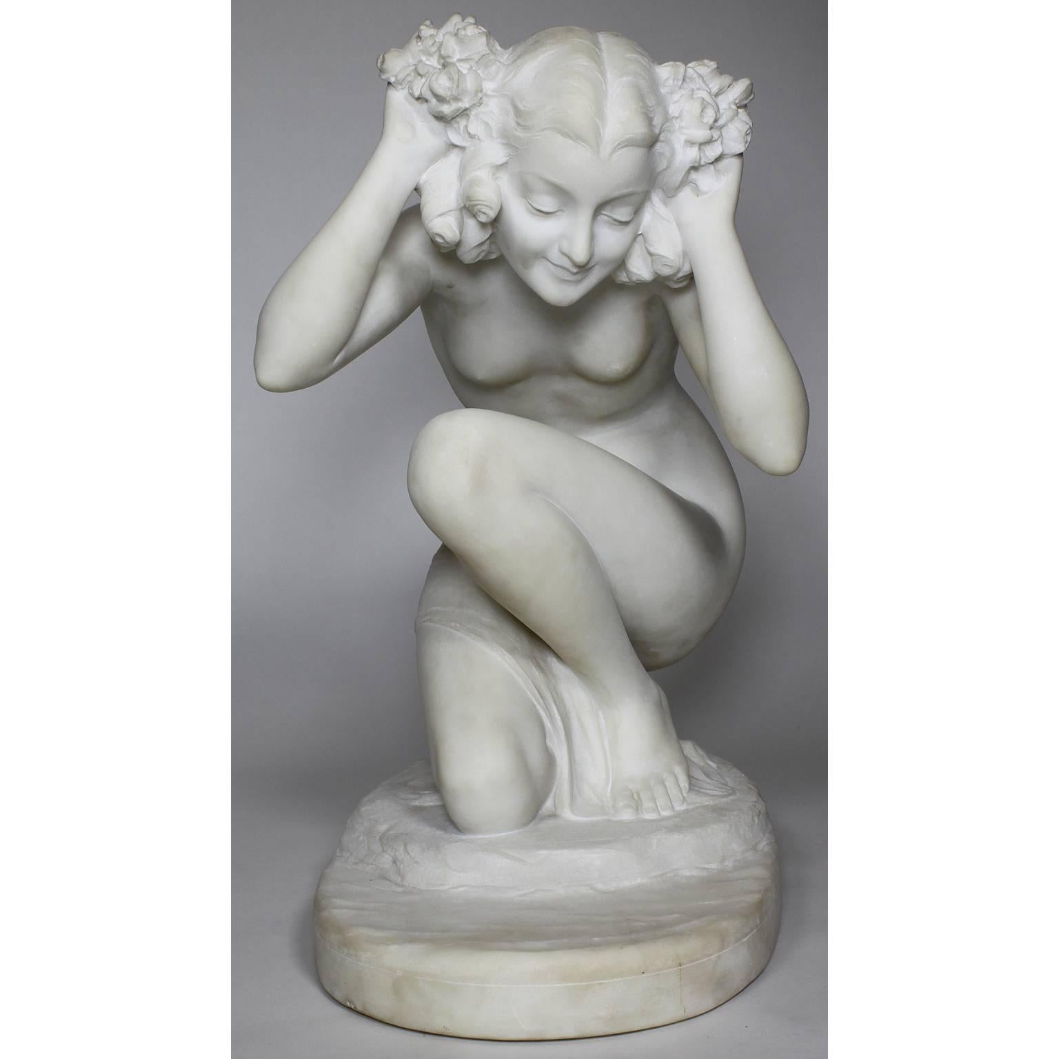 A fine French early 20th century Art Deco white marble figure of a kneeling nude beauty, attributed to Affortunato Gory (Gori) (Italian, 1895-1925). The kneeling nude figure of a young maiden by the shoreline, with her hands up holding a floral