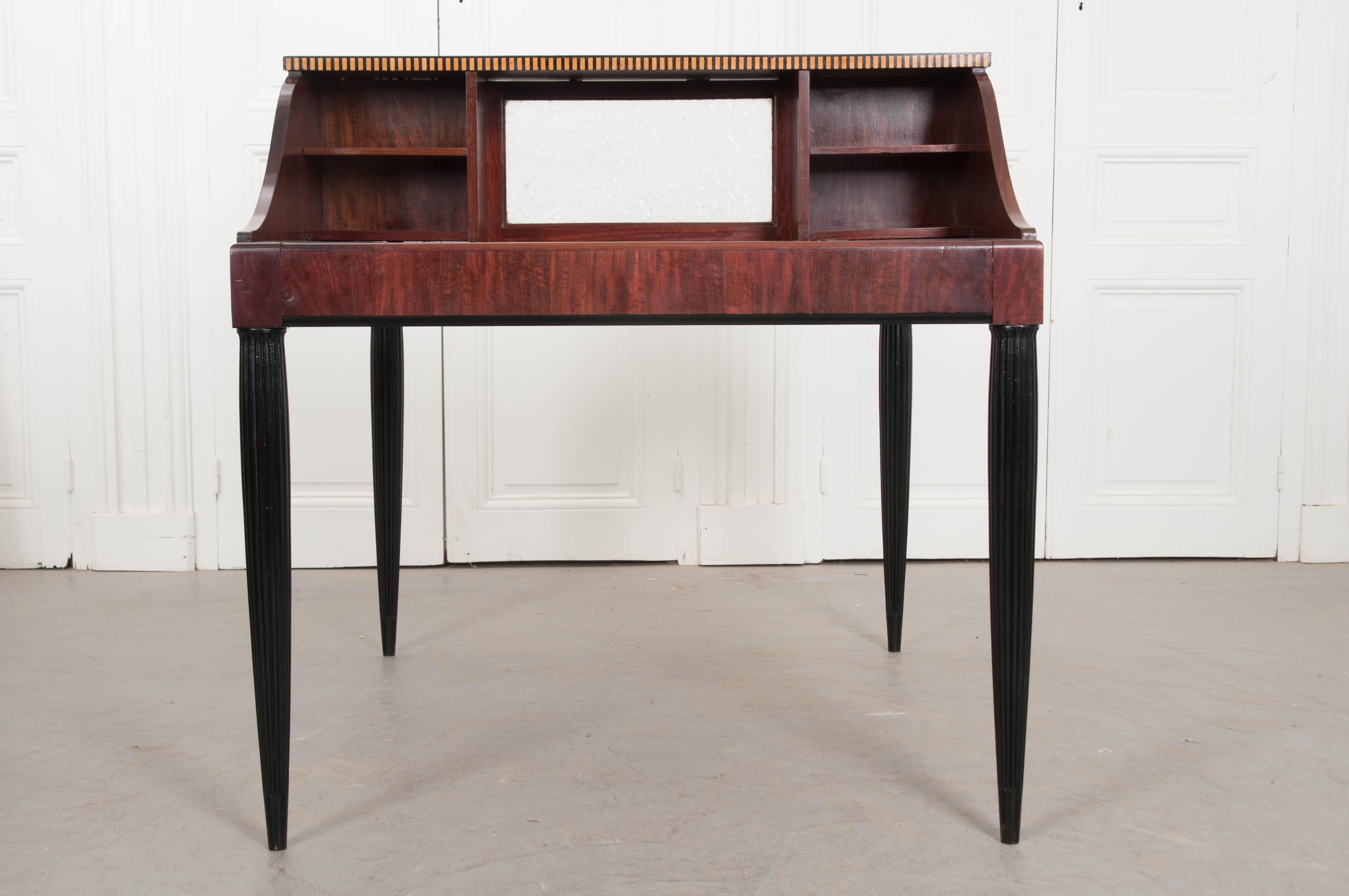 A stylish mahogany Art Deco partners desk, made in France, circa 1920. The two-man desk is separated by eight (total) pigeon holes and a pane of frosted glass. The work surface is topped in a black leather that has been cut to fit the desk