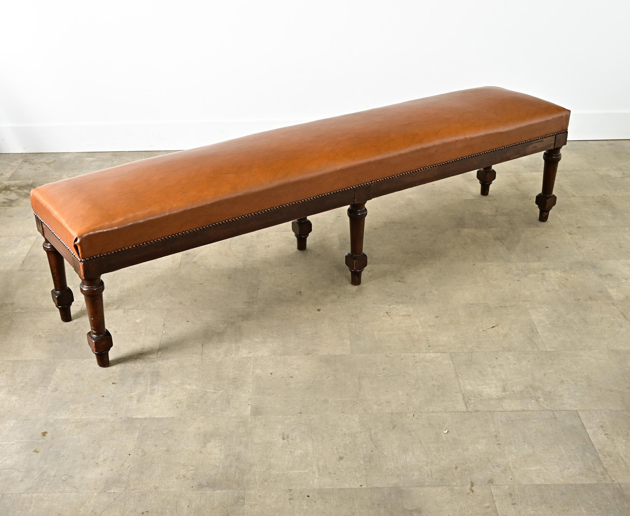 A French oak rectangular bench from the early 20th century with three pairs of turned legs which lift the seat that has been upholstered more recently in a practical, faux leather. The robust proportions of the bench integrate the timeless charm of