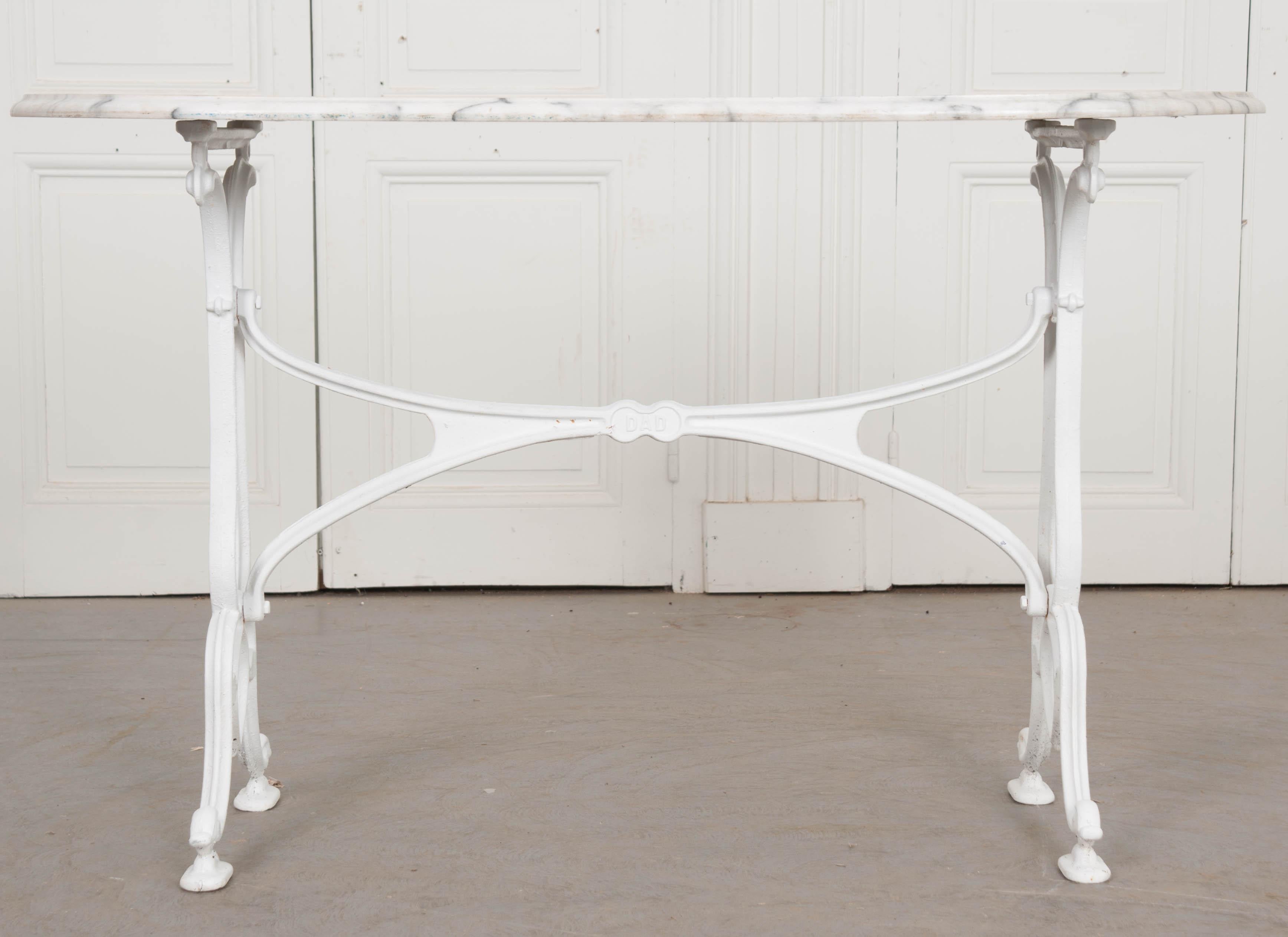A classically styled French bistro table, made there just after the turn of the 20th century. The table features a white marble top, with gray veins, that is in a capsule shape and in wonderful antique condition. It rests atop the cast iron base