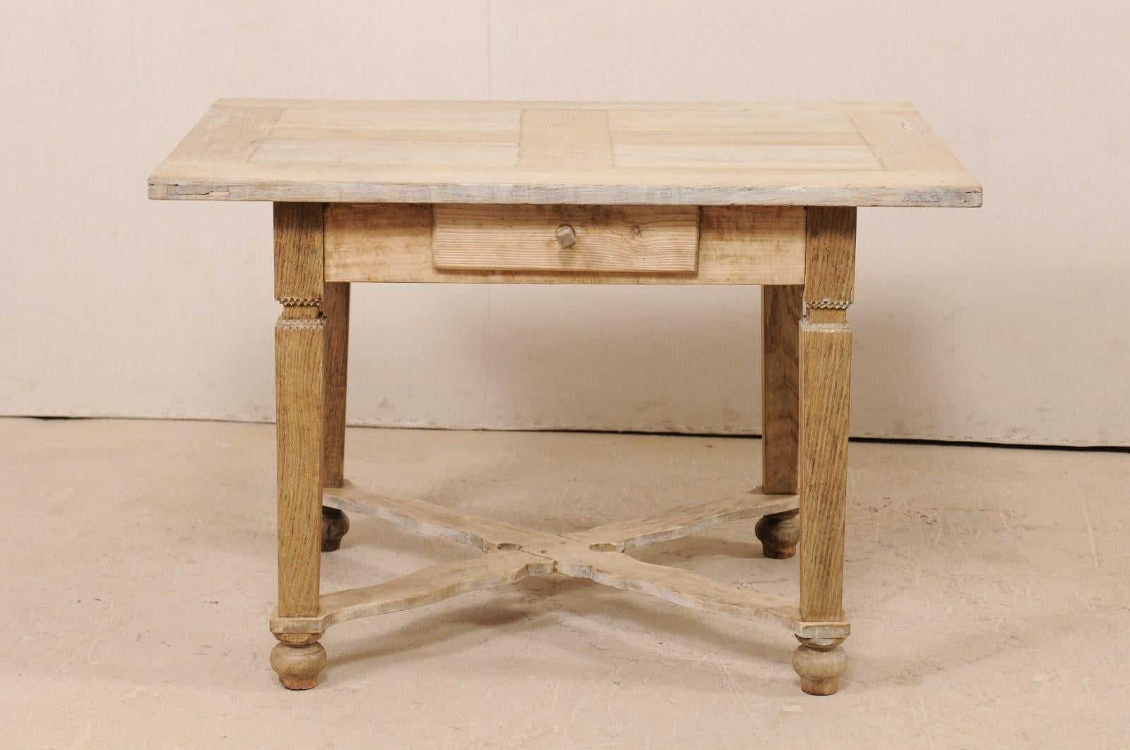 A French early 20th century bleached wood desk or table. This antique table from France features an overhanging rectangular-shaped top, a clean apron with single drawer set into its front centre, and four corner legs which are supported with a