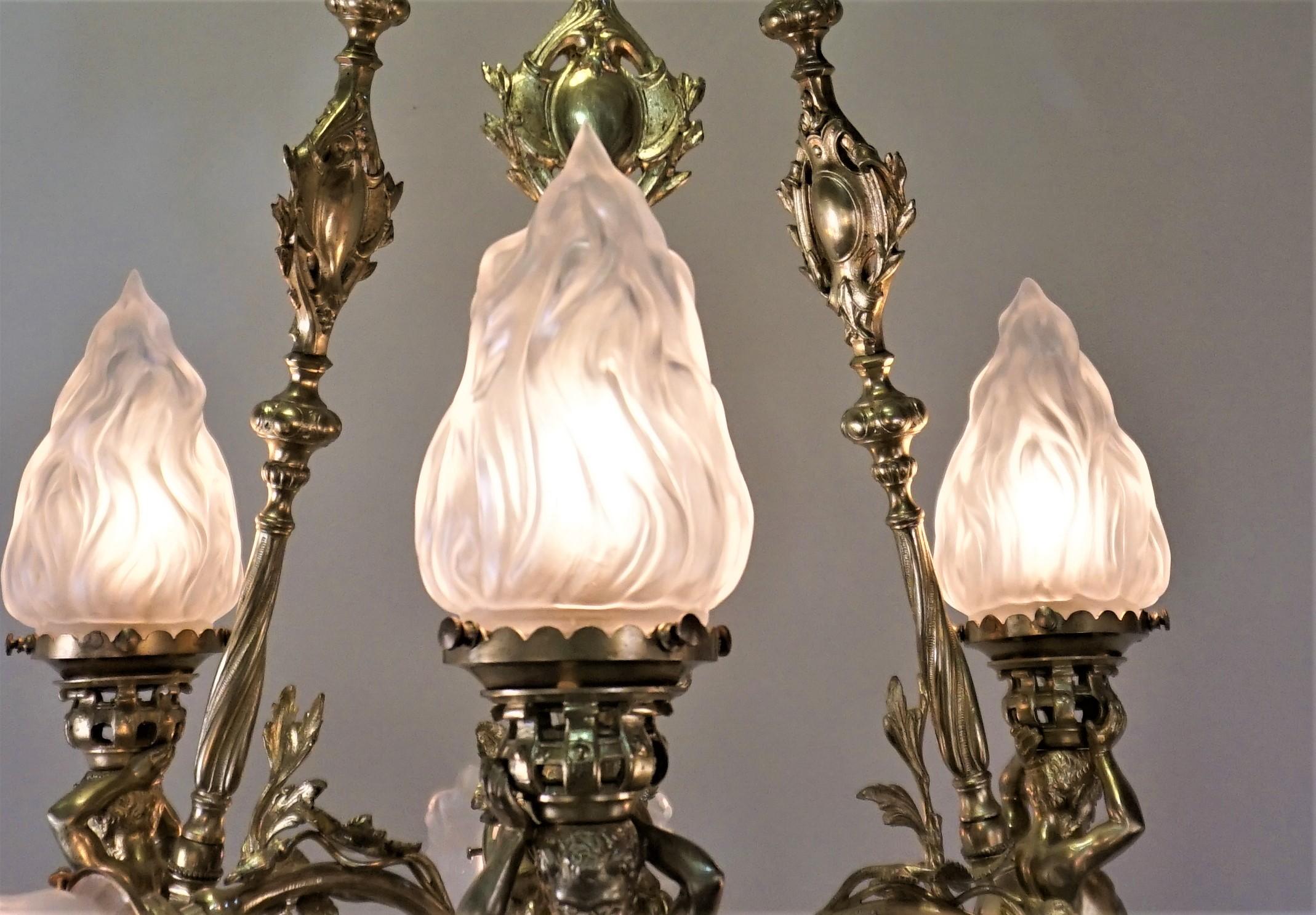French, circa 1900-1910 six-light bronze sculpture chandeliers with flame and flora glass shades.