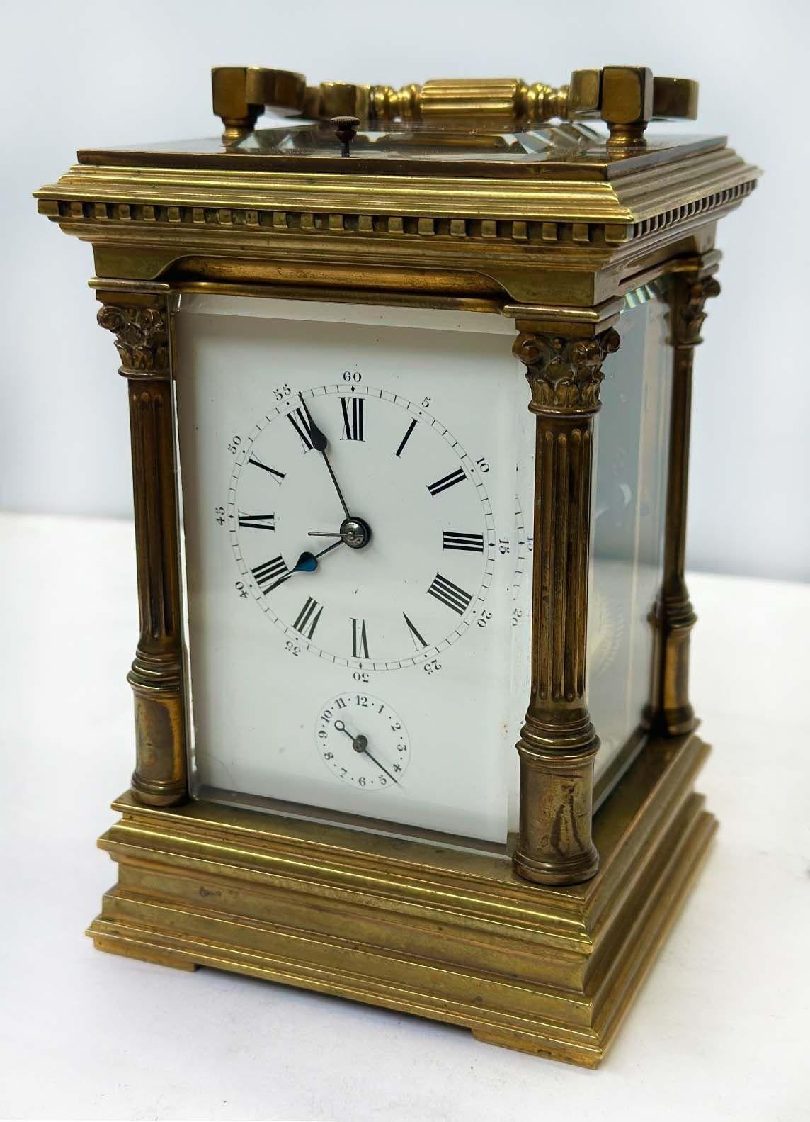 Stunning French brass carriage clock with glass protection by A. Dumas. It is designed with four fluted columns, a dial plate with Roman numerals and more minutes above an alarm setting dial. It is marked on the underside and numbered