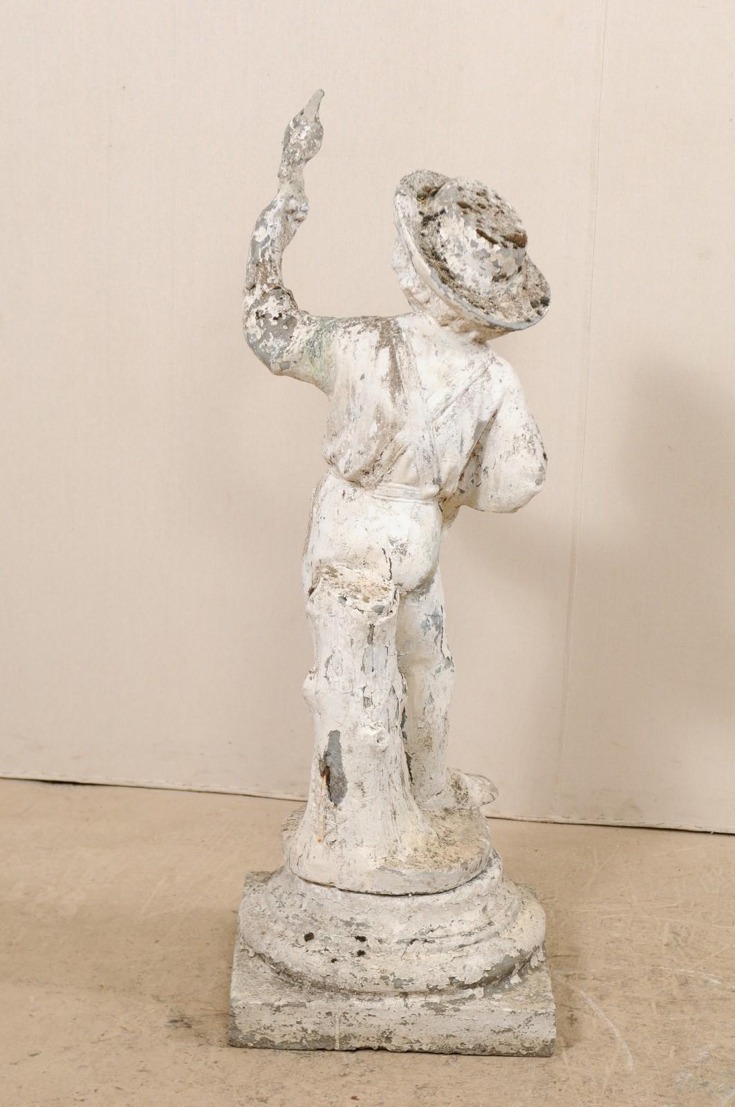 20ième siècle Sculpture de jardin ancienne en pierre moulée représentant un garçon avec un oiseau, d'une hauteur de plus de 2 mètres. en vente