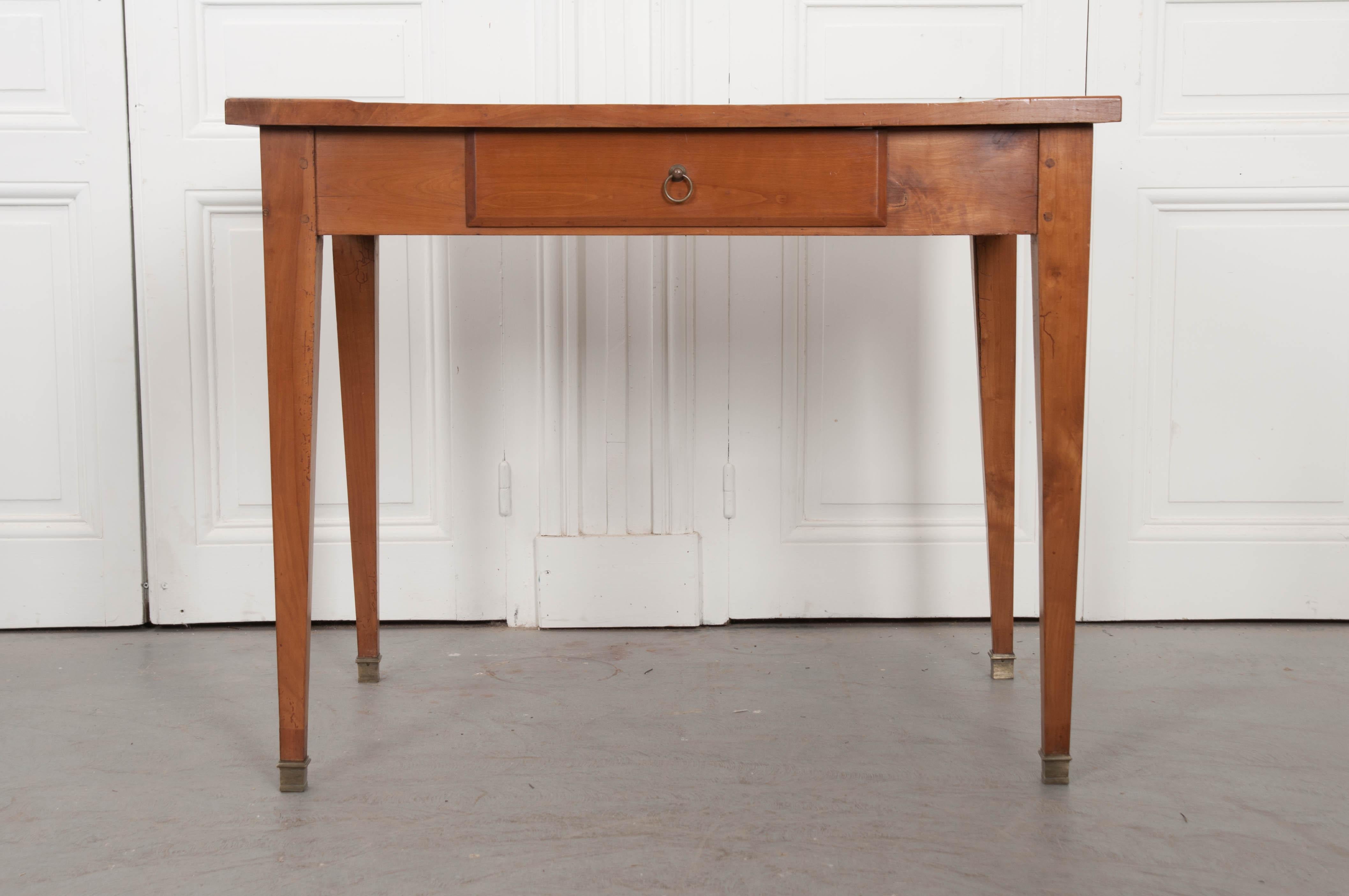 This elegant Directoire-style writing table, was made in France circa early 1900s, of pegged construction. The writing surface is covered in a gilt-tooled amber leather which exhibits a warm patina consistent with age and use. The apron is fitted