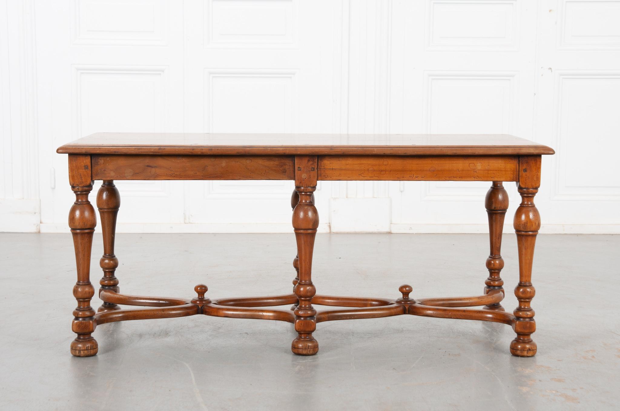 A beautiful French fruitwood low table, made in the early 1900s, featuring expertly turned legs and curved stretcher details. Vibrant and wonderfully patinated. This fantastic little table would make the perfect coffee or cocktail table, but could