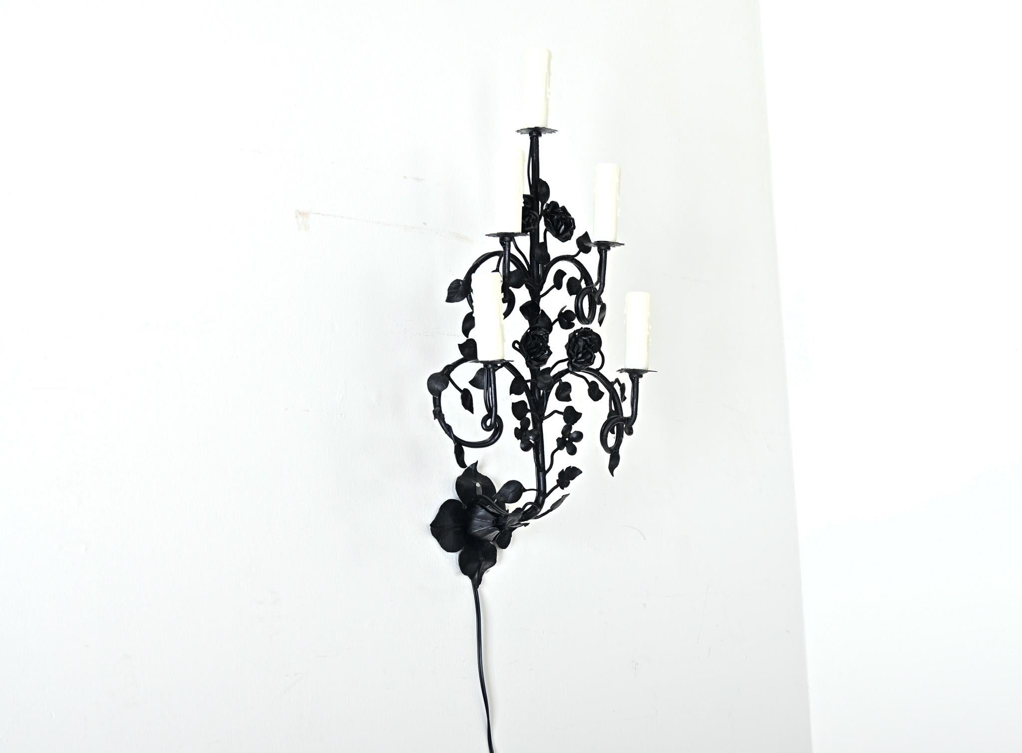Aplique de pared francés de hierro negro de principios del siglo XX (hacia 1930), de tema foliado, con ramas que se desplazan como las de una espaldera, en las que florecen pequeñas rosas o gardenias. Este accesorio único contrasta el simbolismo