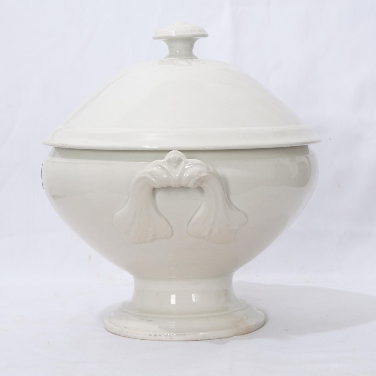 A gorgeous early 20th century, circa 1900, white ironstone tureen with fitted lid, from France. The stylish lid features a detailed knob handle. This tureen is perfect for serving soups, stews, or gumbos. Two handles are fashioned onto the sides.