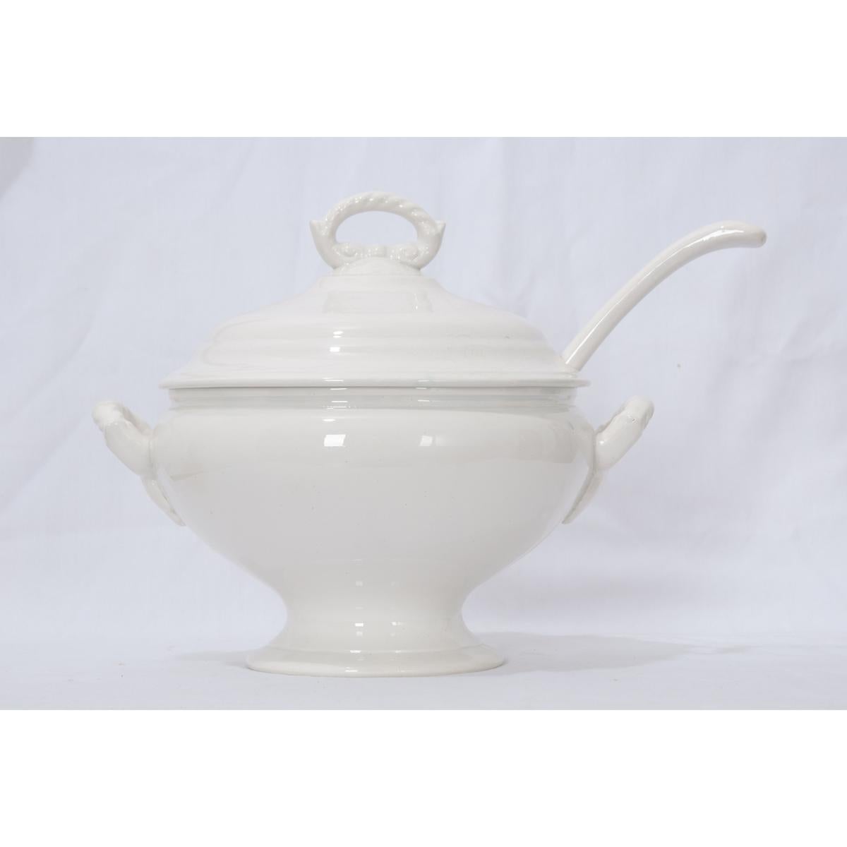 A gorgeous early French 20th century, circa 1900, white ironstone tureen with fitted lid and ladle. The stylish lid features a detailed pull handle. This white interior finish is clean, perfect for serving soups, stews, or gumbos. Two handles are