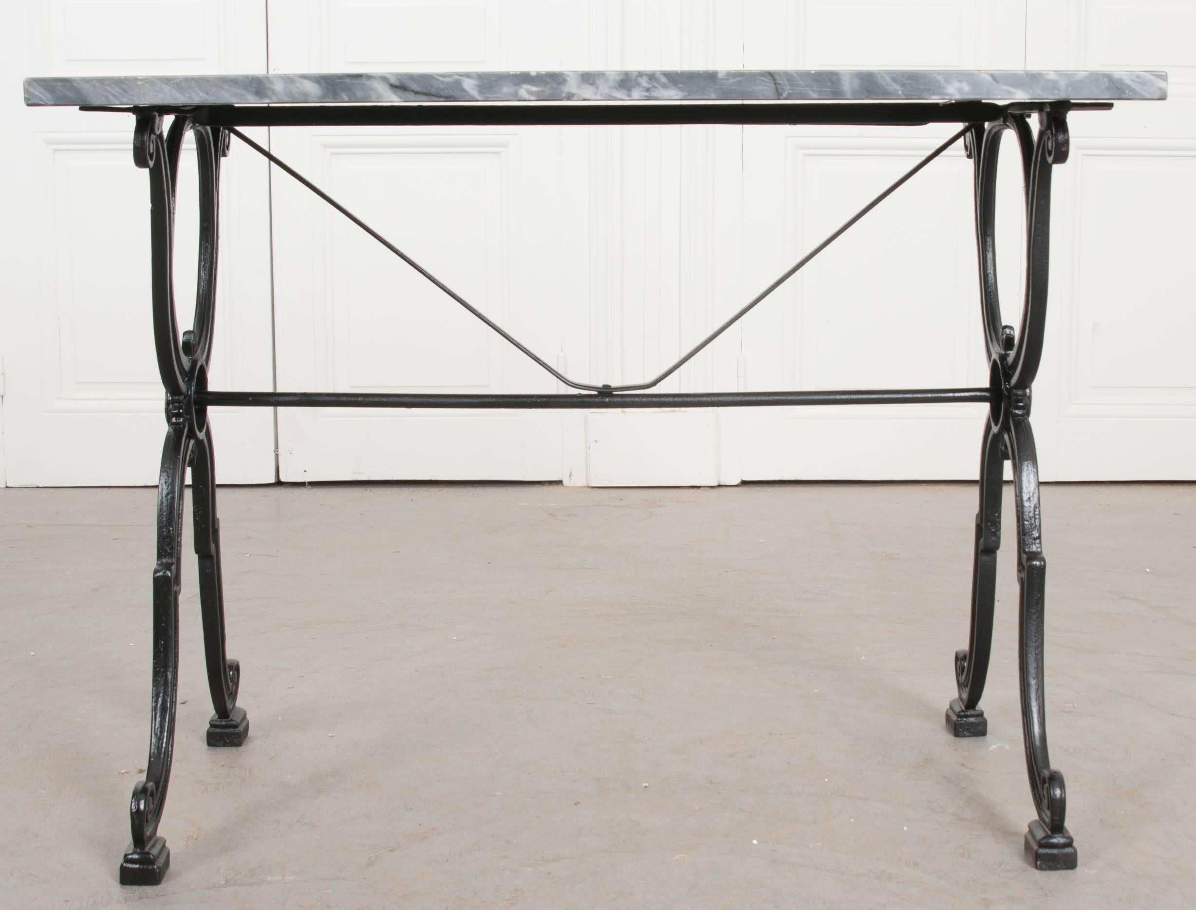 An outstanding French marble-top garden table, with iron base, made at the beginning of the 20th century. The gray marble top is in wonderful antique condition, with white streaks present throughout. The iron base is classically styled, with