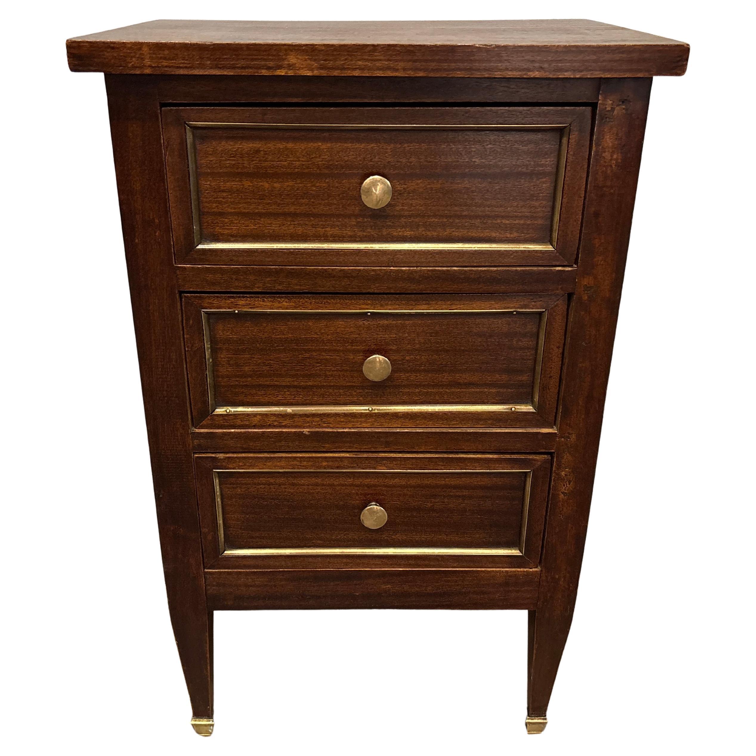 This charming piece is made of dark mahogany with brass around the frame of the drawers. it can be used as a night stand or anywhere else.