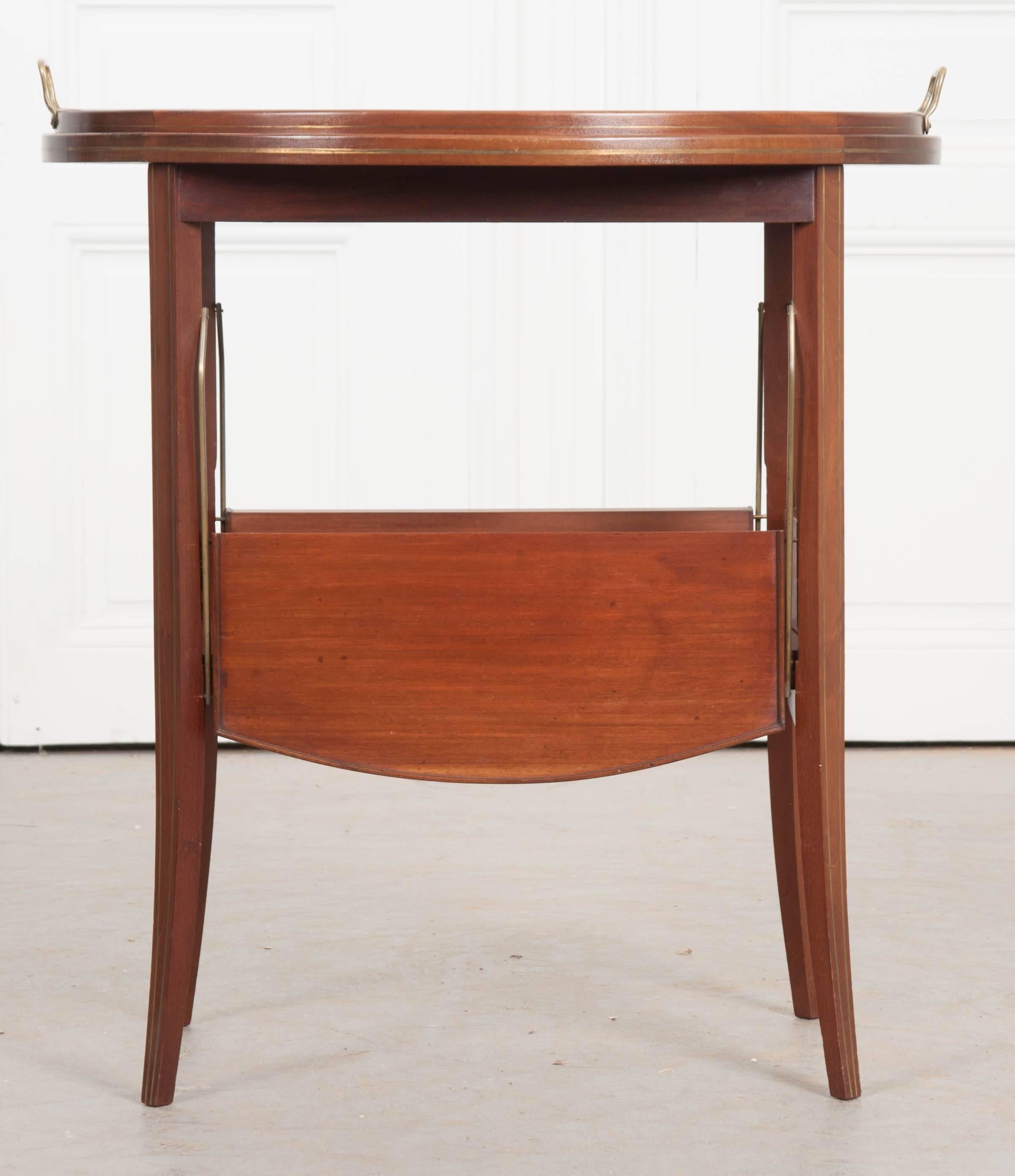 A wonderful mahogany tea table, circa 1910 from France. This early 20th century piece is in great antique condition, with the original tray top. This oval glass tray rests in the table’s welled mahogany top and is complete with brass handles. The