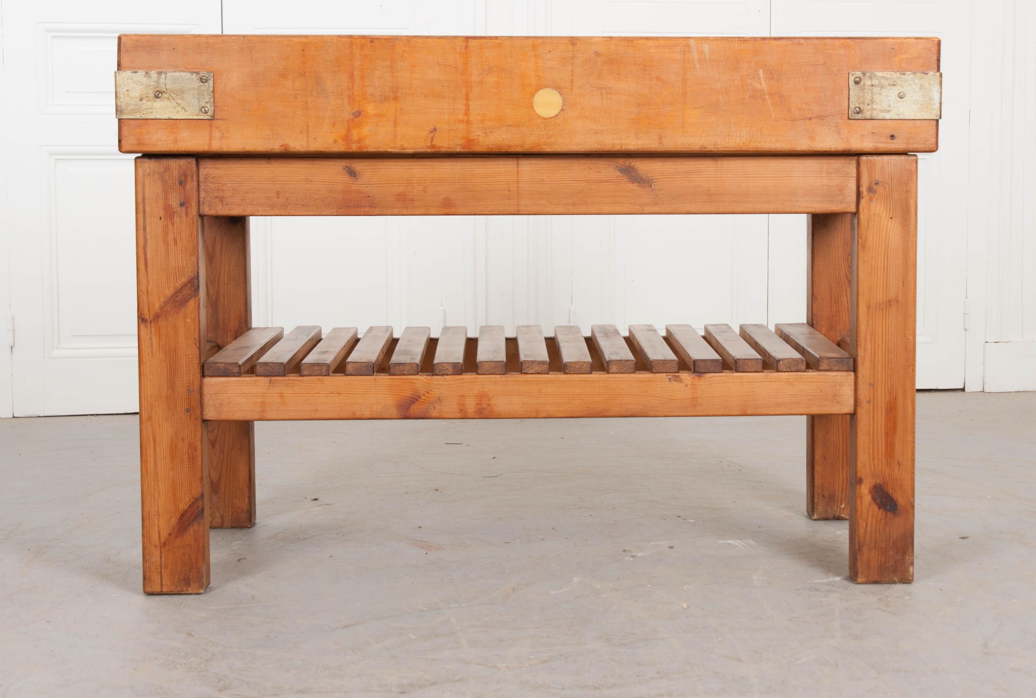 A substantial pine butcher block, from 20th century, France. The table’s top is made from thick pine blocks that have been tightly joined together and bound with steel bindings. The work surface has acquired some patination from years of knife and