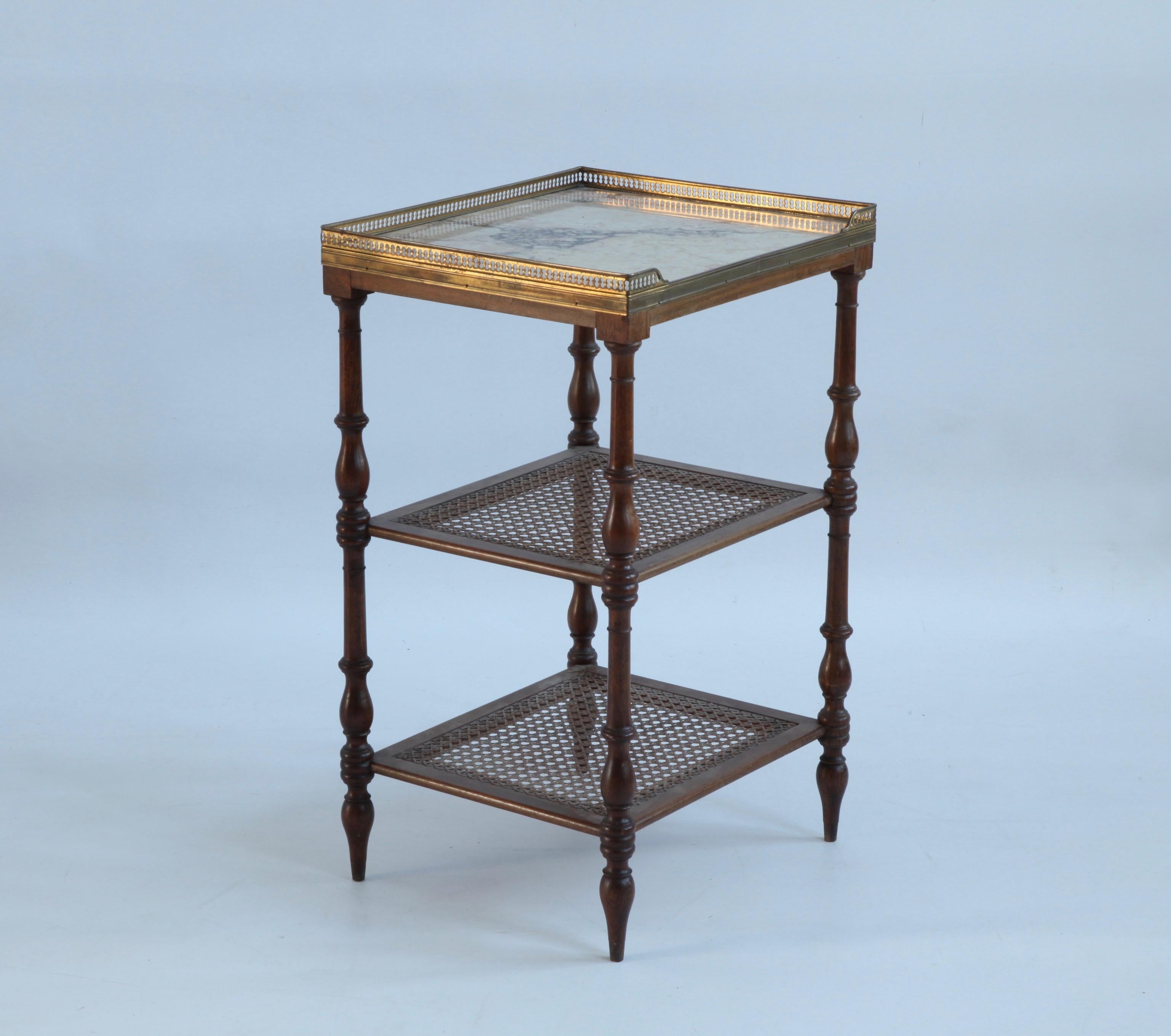 A French, freestanding shelving unit made at the turn of the 20th century in walnut with turned legs, a marble top trimmed with delicate brass fretwork and two wicker shelves. Neat and beautifully made.
