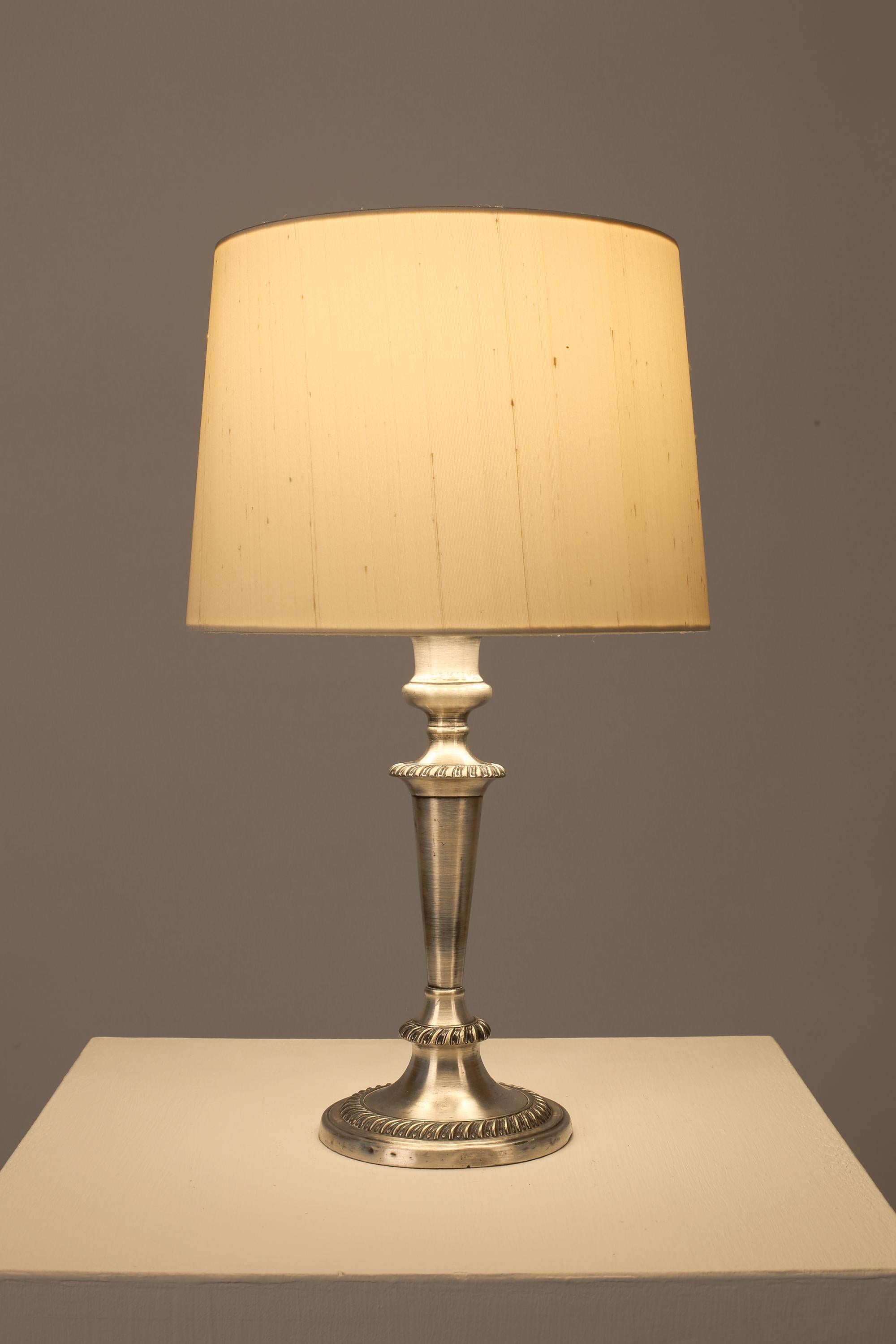 Un'elegante lampada da tavolo in ottone argentato dei primi del Novecento dalla classica forma a candeliere. Si dice che provenga dalla reception di un hotel della Riviera, con la scritta 