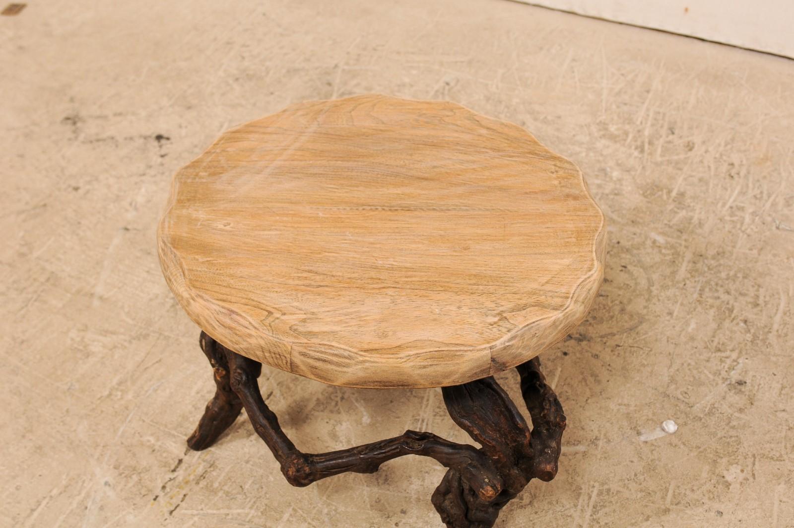 Une table basse française de petite taille avec une base en vigne du début du 20e siècle. Cette merveilleuse table ancienne de France présente un plateau rond en dalles de bois avec des bords festonnés sculptés, au sommet d'une base en vigne