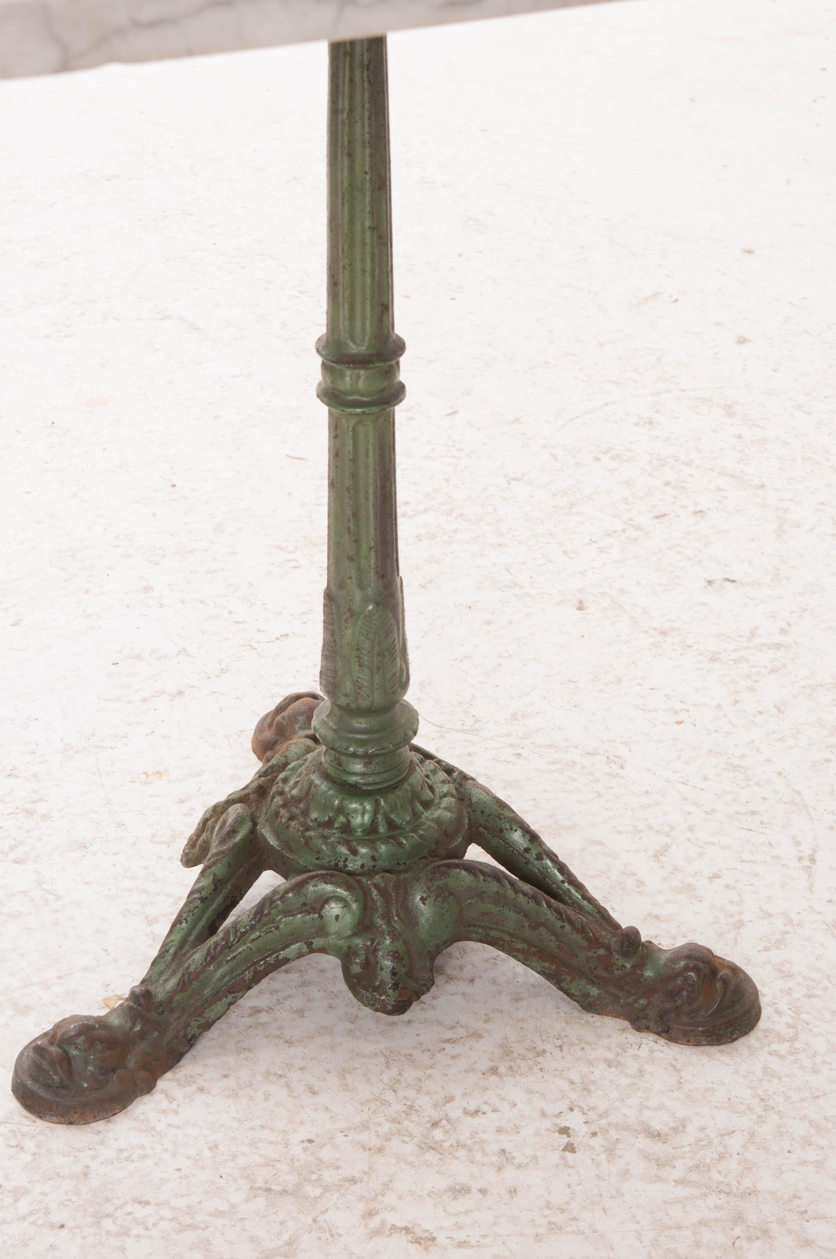 This fabulous cast iron bistro table is outfitted with a beautiful square white marble top and comes from 1920s France. The iron tripod base is painted green with Classic styling and a marvelously aged patina. The white marble top also boasts an
