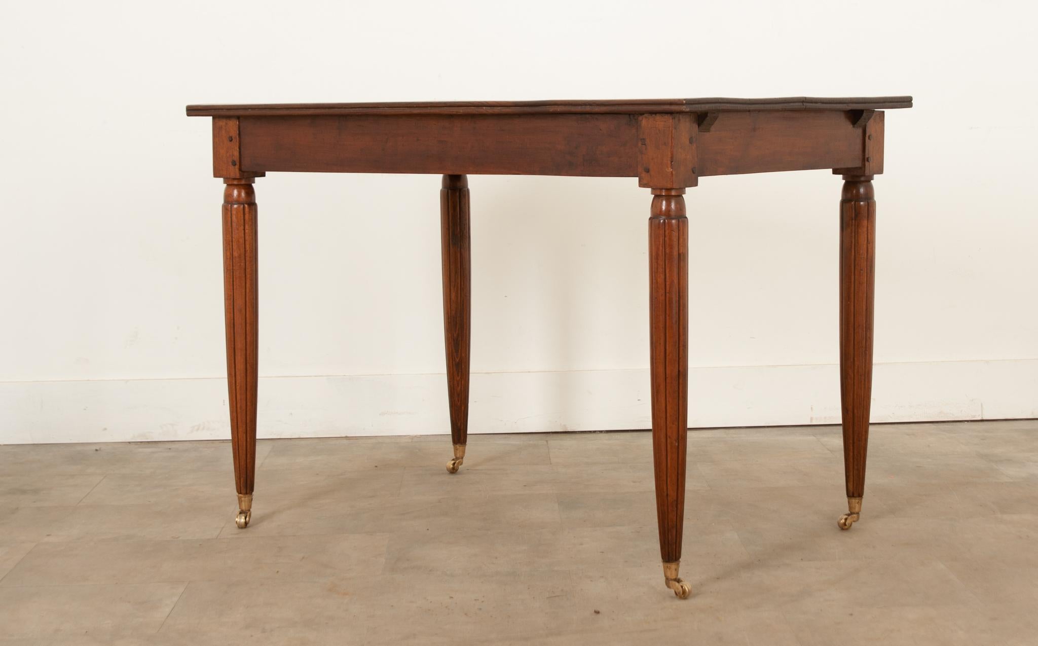 A fantastic French solid walnut  bistro table, made about the turn of the Century. This unassuming table has subtle stylings that make it anything but simple. Beautiful expression can be found in the grain of the walnut, which has a uniform and