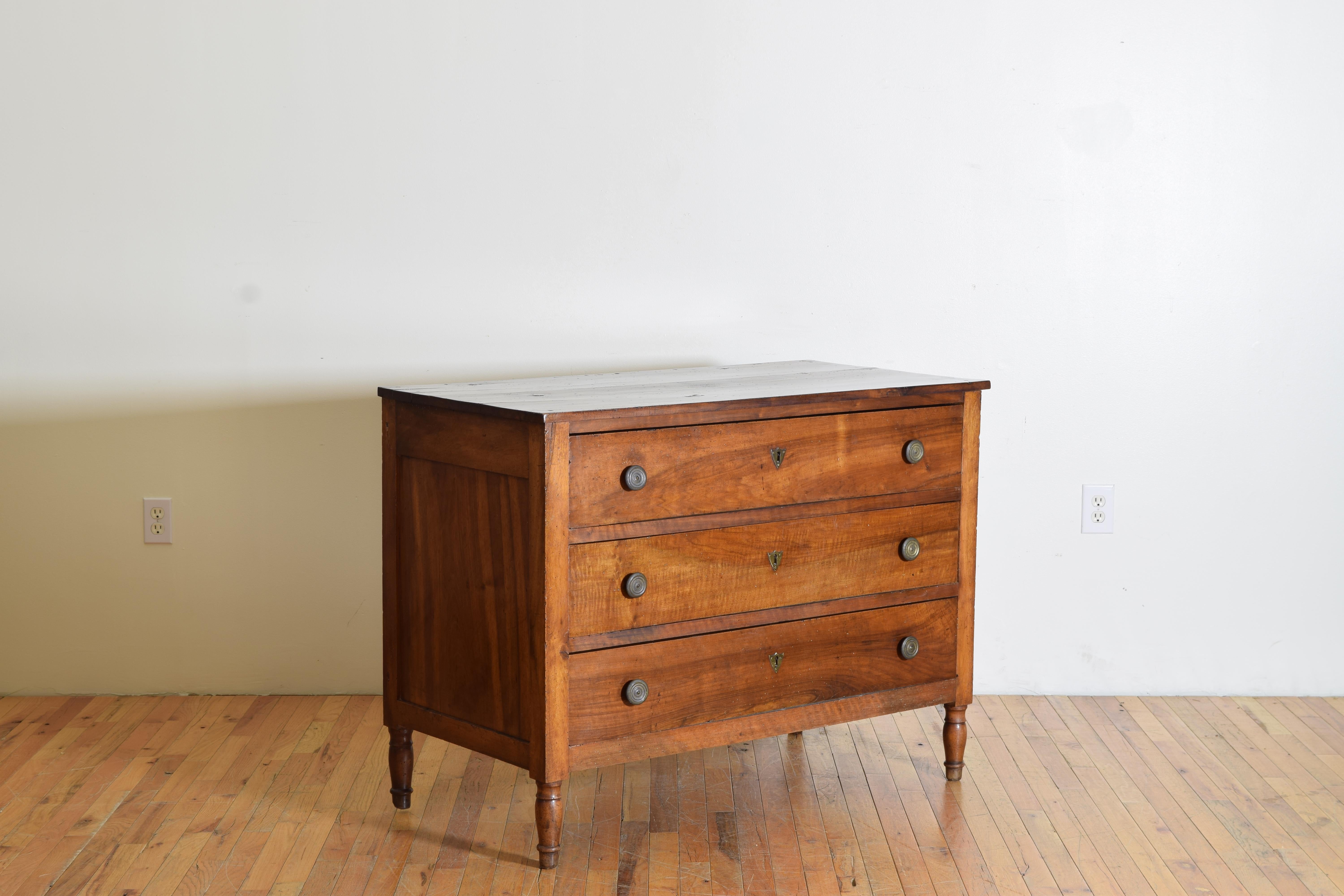 Having a rectangular top resting on a conforming case housing three drawers with circular bronze pulls, the case raised on turned slightly tapering legs