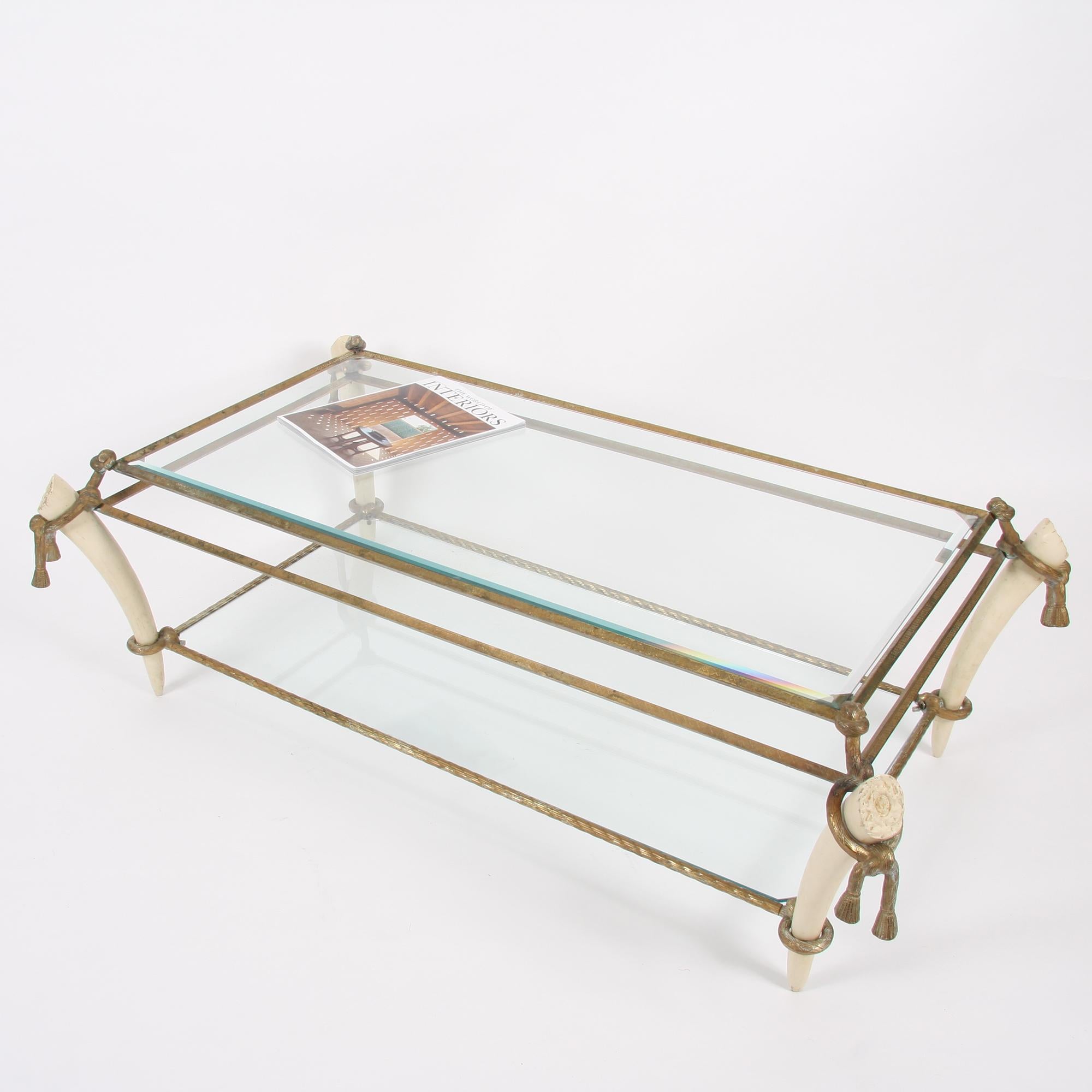This elegant, exquisitely detailed two-tiered glass and brass table with faux ivory legs dates back to 1930s, France.
