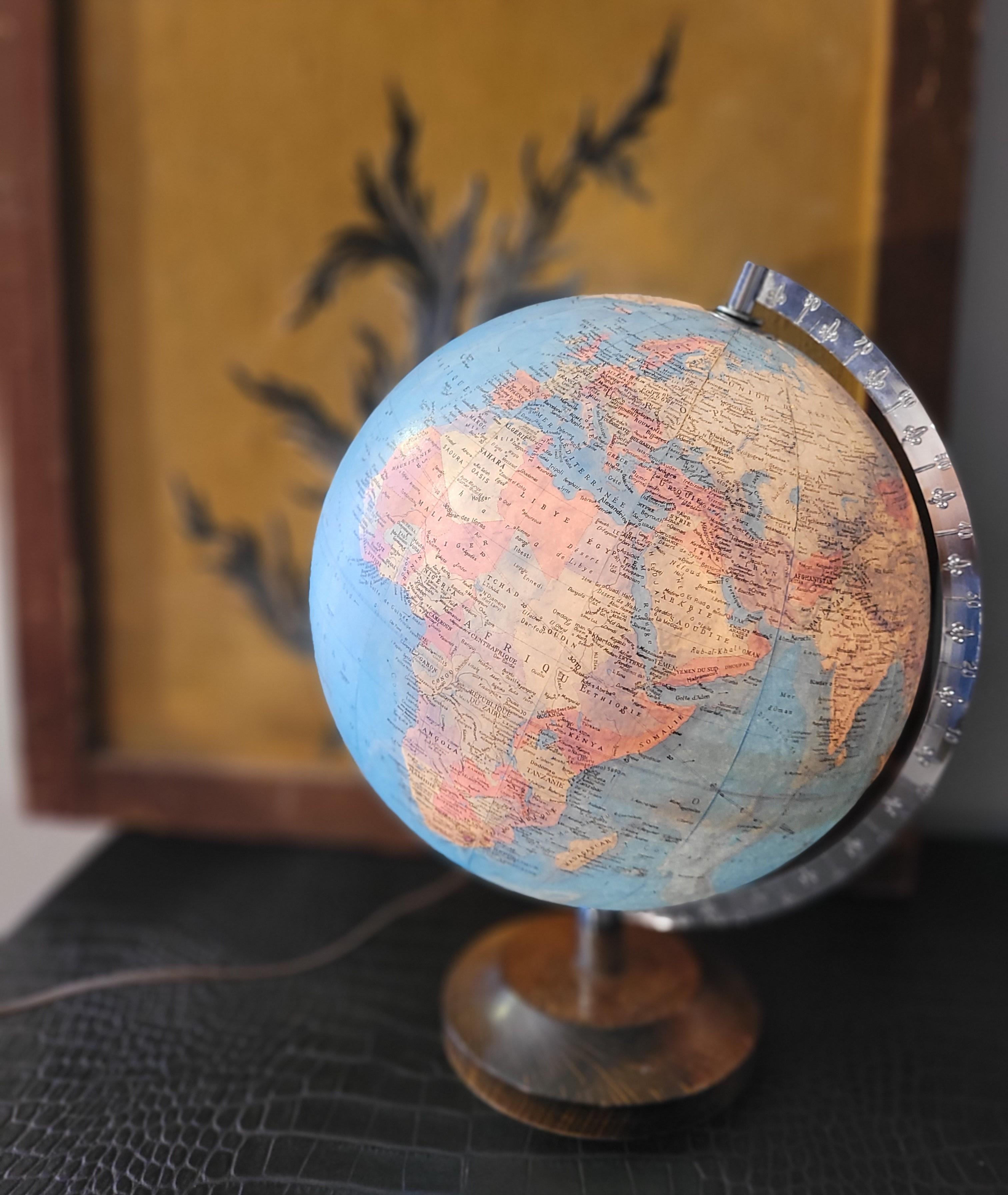 Earth Globe made of cardboard with interior light, original from the 60s, of French origin. Therefore, the names of the countries, regions, oceans... are represented in French, and the entire surface of the metal shaft is decorated with