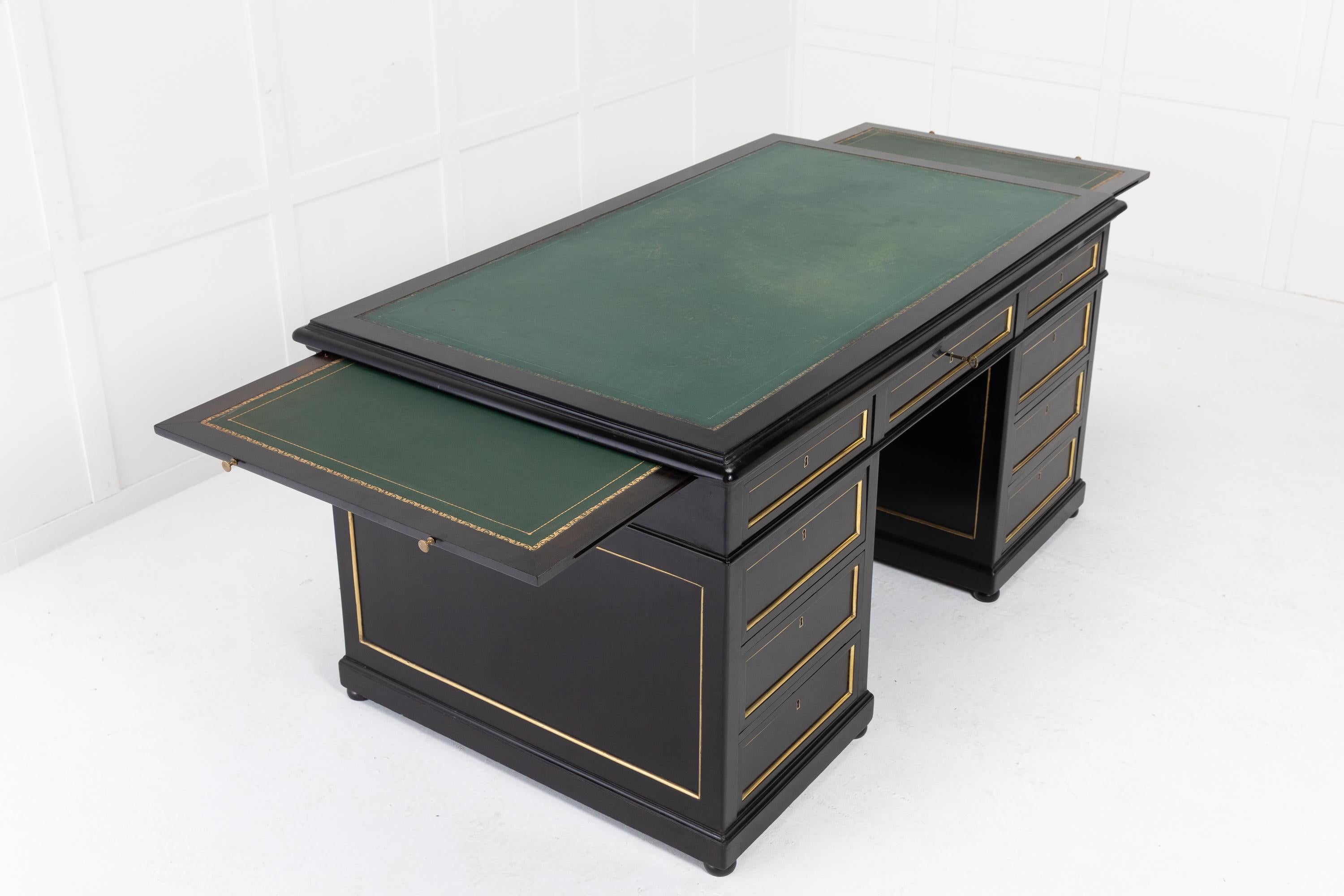 A good sized French ebonised pedestal desk of nine drawers, each with brass mouldings and escutcheons. Having an inset, tooled old leather writing surface. There are pull out slides to either side with small brass pull handles. The sides and the