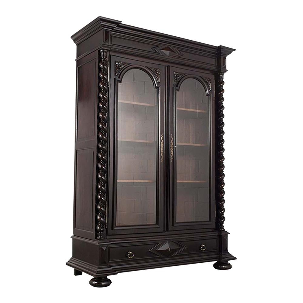 This French Late 19th Century Renaissance Style Bookcase has been fully restored and is made out of walnut wood with a new ebonized & patina finish. The bookcase features carved spiral columns on each side, hand-carved details, and two large glass