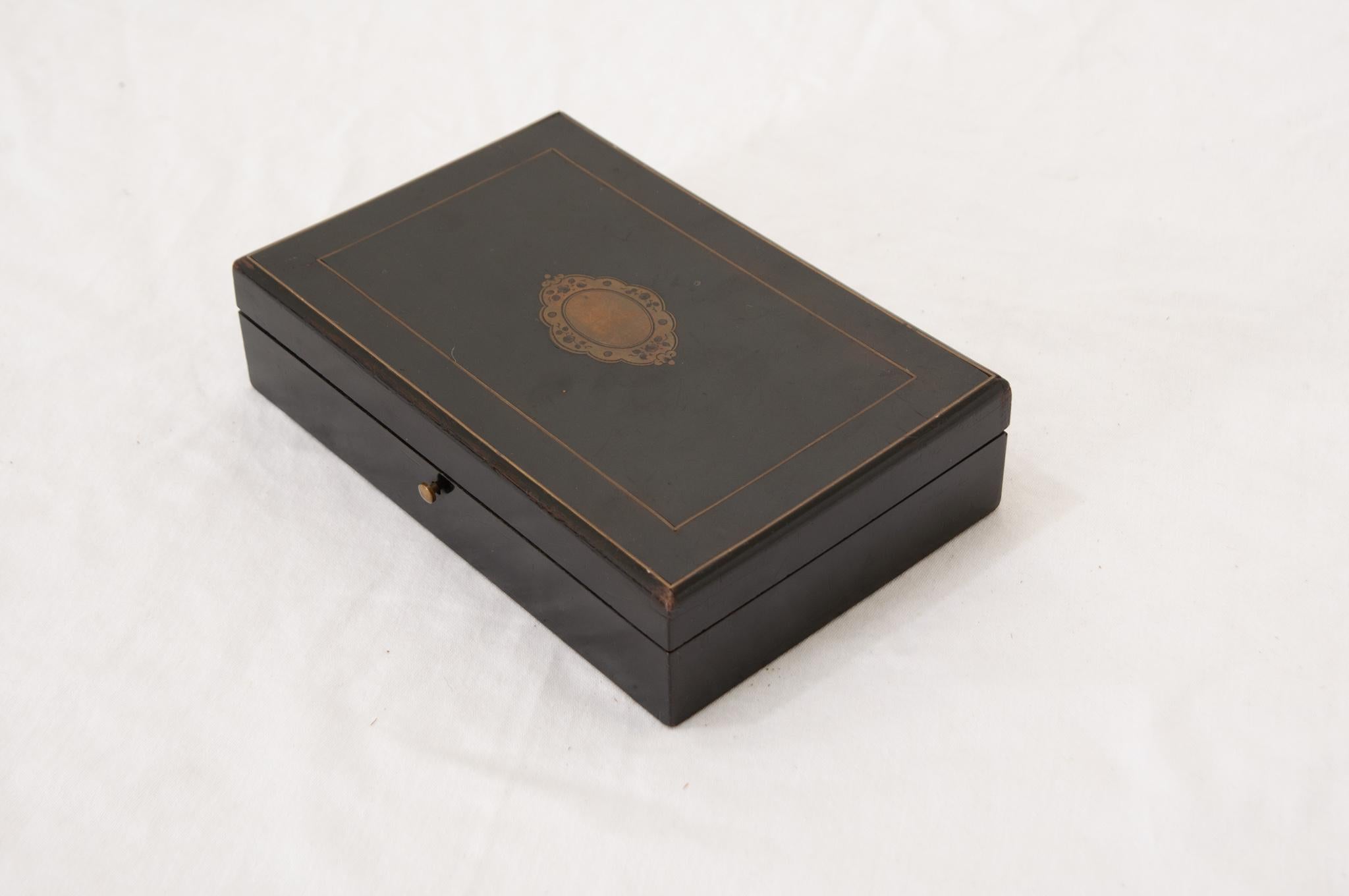 A French 19th Century decorative box opening on brass hinges. Inside you’ll find the box is fitted with two levels of storage with five compartments. This is most likely used for storing jewelry. This handsome box features ebonized wood with a brass