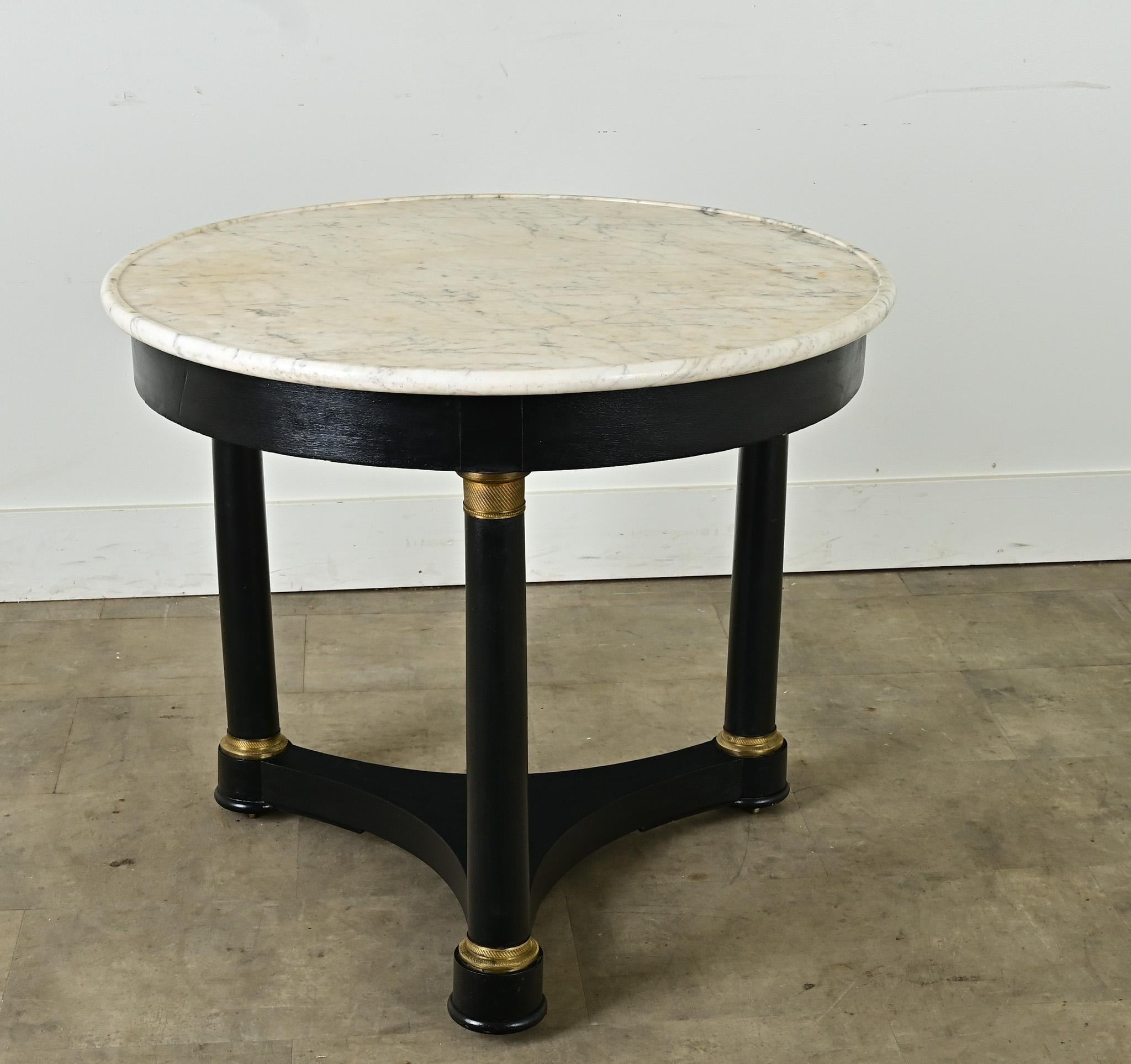 Classique, table ronde Empire français à plateau de marbre blanc sur une base tripode avec une finition peinte récente. Le dessus en pierre tachetée est principalement blanc avec de légères veines grises et présente un rebord surélevé sur le