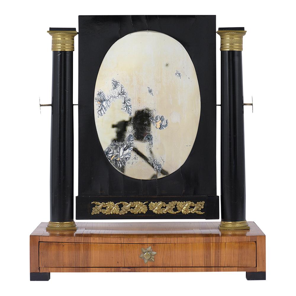 This 19th century French Empire Vanity table mirror is in good condition still keeps its original mahogany and ebonized color combination finish newly refurbished. The mirror is held by two carved wood ebonized columns with intricate brass accents