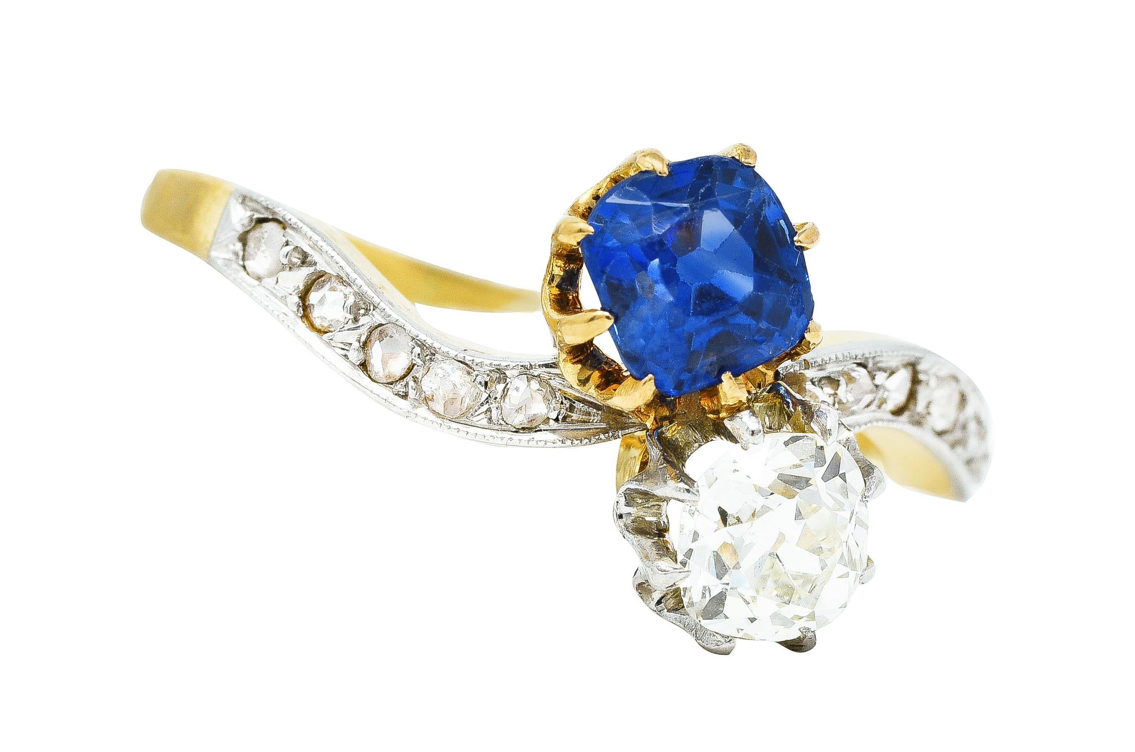 Bypass ring in a double stone Toi et Moi style - French to mean 'You and Me'. Featuring a cushion cut sapphire weighing approximately 0.85 carat. Transparent with vibrant violetish blue color. Coupled with an old mine cut diamond weighing