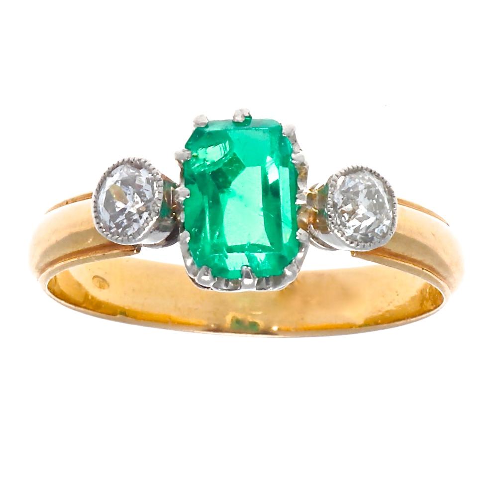 We found this beauty in France and the decision to bring it back to you was instant. This 3 stone ring features a vibrant green emerald and 2 old European cut diamonds. The emerald is set in scalloped platinum prongs while the diamonds are bezel set