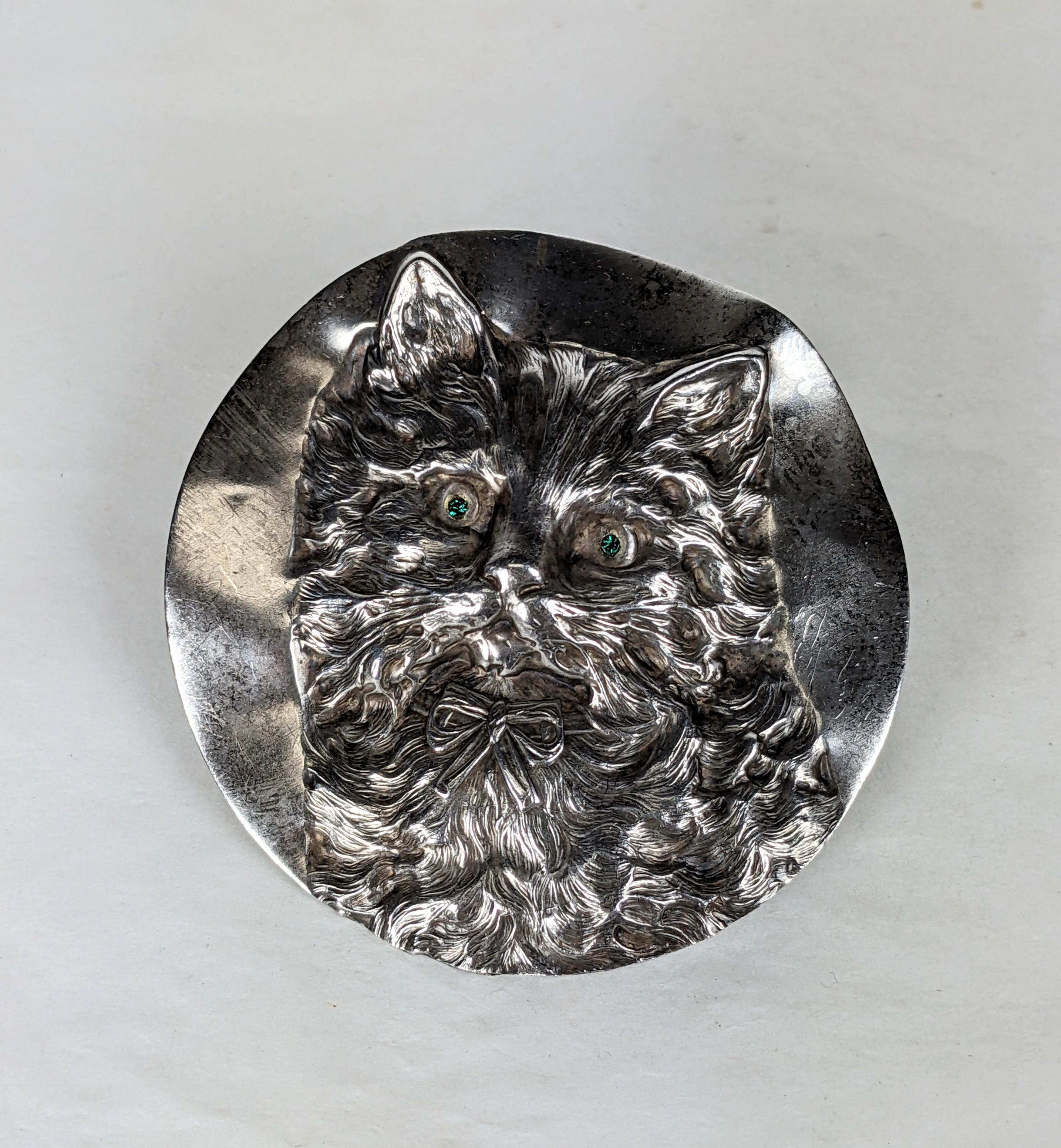 Large Edwardian repousse cat portrait brooch. The  round free form brooch of silver plate with wonderful detailing and bright emerald crystal eyes. French clasp fitting. Excellent Condition, L  2.75