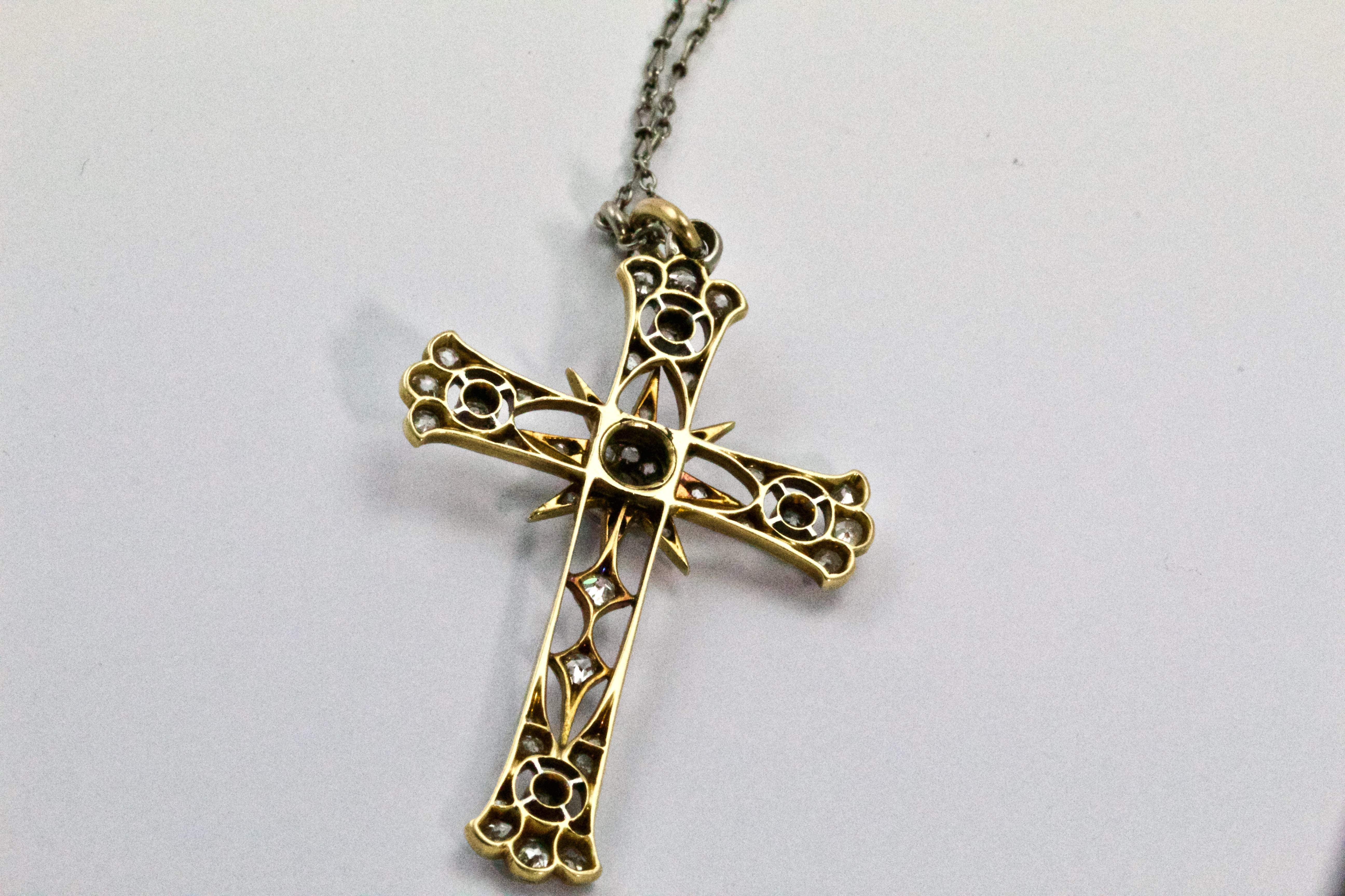 A stunning French Edwardian yellow and white gold cross pendant! With a fine open worked body and set with rose cut diamonds and millegrain detail throughout, suspended from a platinum period chain this is the ideal addition to any collection!