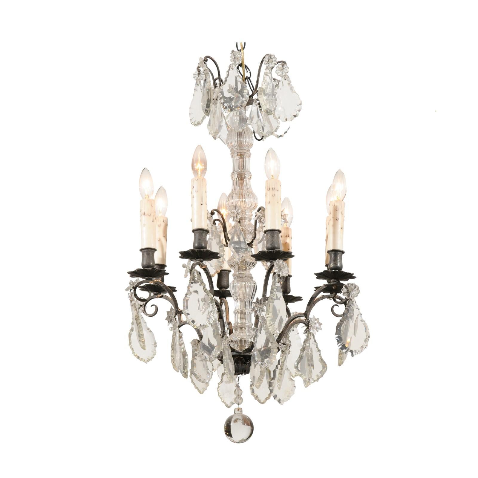 A French eight arms crystal chandelier from the 19th century, with metal armature. Born in France during the 19th century, this exquisite crystal chandelier features a central column topped with delicate pendeloques and rosettes. The lower section