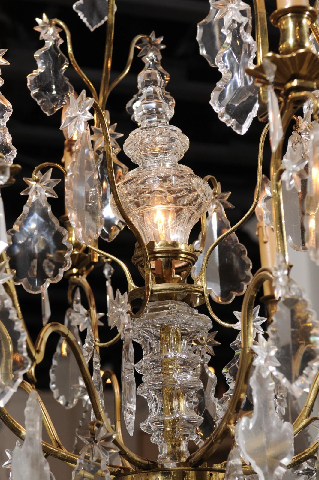 A French eight-light crystal chandelier from the early 20th century, with gilt metal armature and pendeloques. Born in France during the Turn of the Century, this exquisite chandelier features a gilt metal armature, supporting a variety of crystals