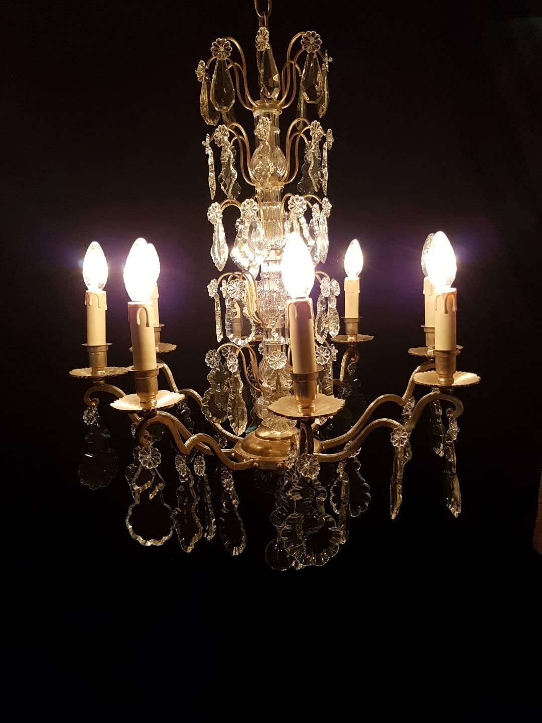 French chandelier with eight-candle lights and five layers of pendologues in the centre. Beautiful piece with a very nice silver-colored patina. 

This is just one of our large collection chandeliers. Besides the old and antique chandeliers we
