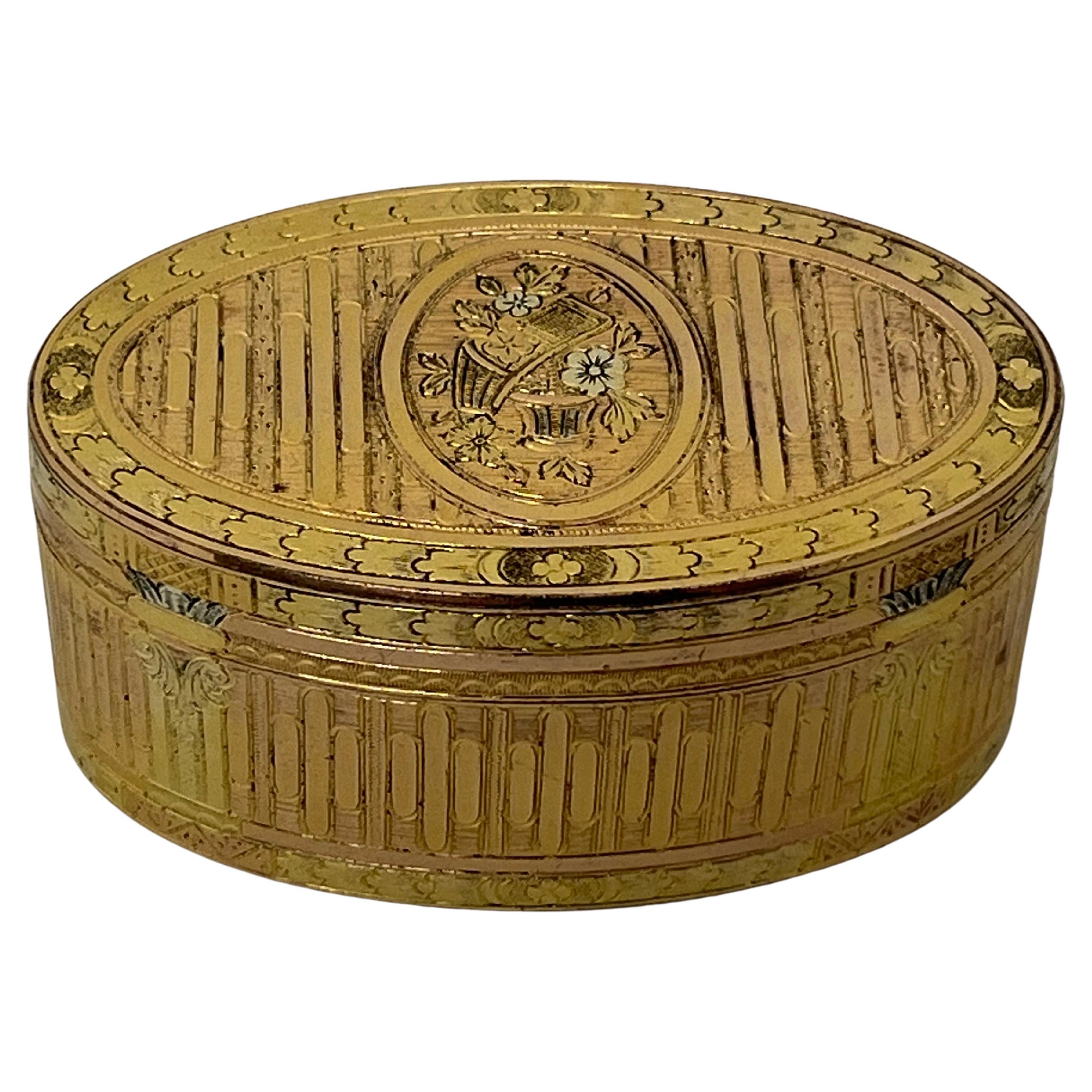 French Eighteenth-century silver-gilt snuff box, of outstanding quality, oval form with varicoloured gilding, the top cover and base with central oval vignette depicting baskets and flowers. With yellow coloured gilding to the body, contrasting with