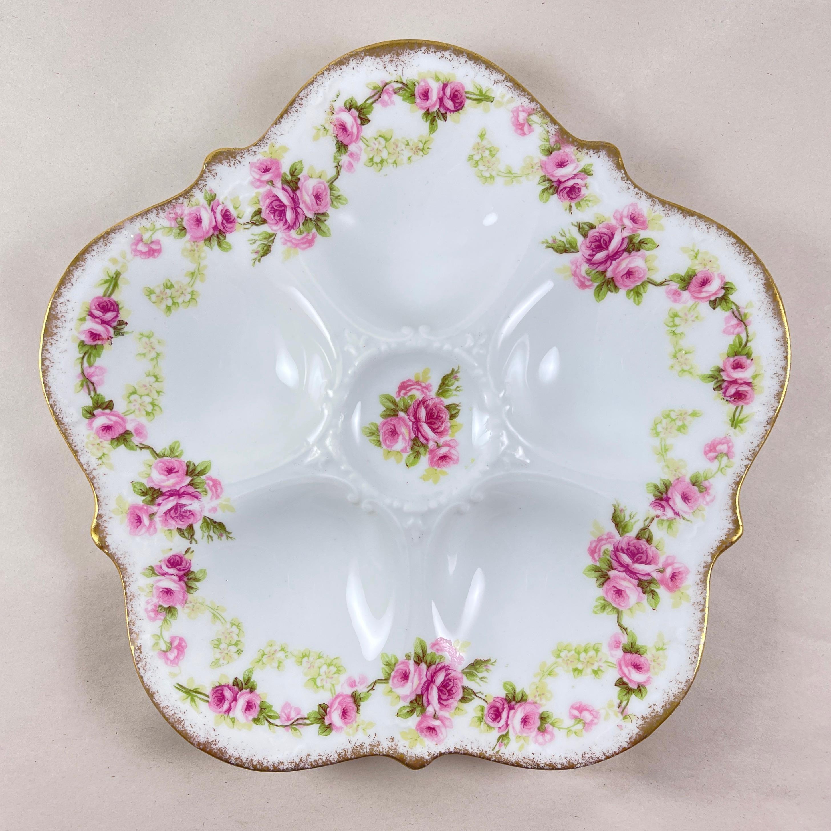 Un plato de ostras de porcelana Elite Limoges, Francia, hacia 1890.

Decorada con guirnaldas corridas de rosas rosas y rojas, junto con guirnaldas menores de flores de pétalos de colores más claros,  esta ostra de cinco pocillos tiene un borde