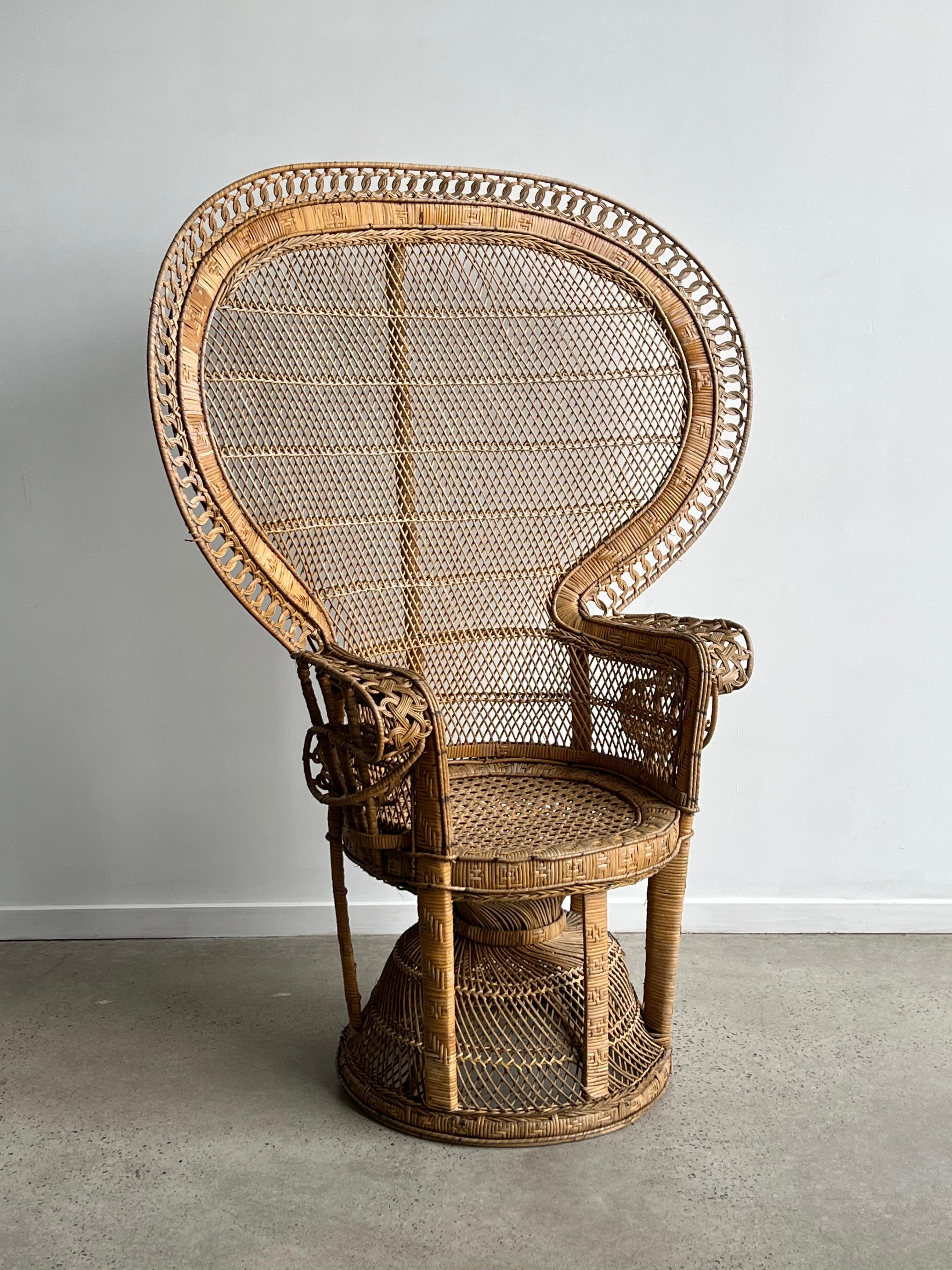 An original example of the iconic “Emmanuelle” peacock chair. The chair features expertly woven wicker and cane with a large-scale fan back, portraying a peacock’s splayed tail. 
This chair wants to be seen, so its status as a sex symbol makes it a