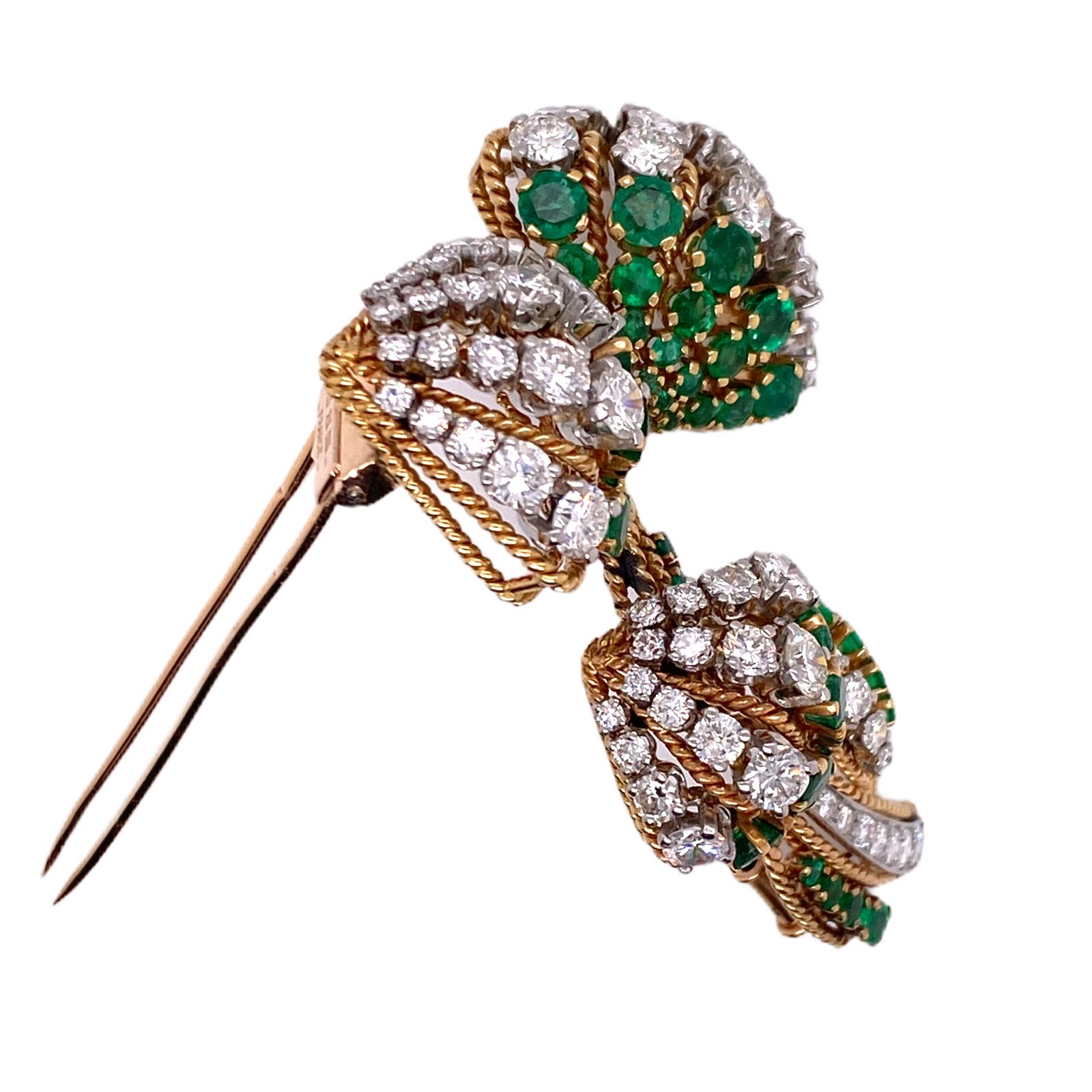 Gorgeous French diamond and emerald brooch fashioned in 18 karat yellow gold and platinum. The pin features 76 round brilliant cut diamonds weighing approximately 8.00 carat total weight and graded F-H color and VS clarity. In addition,  the brooch