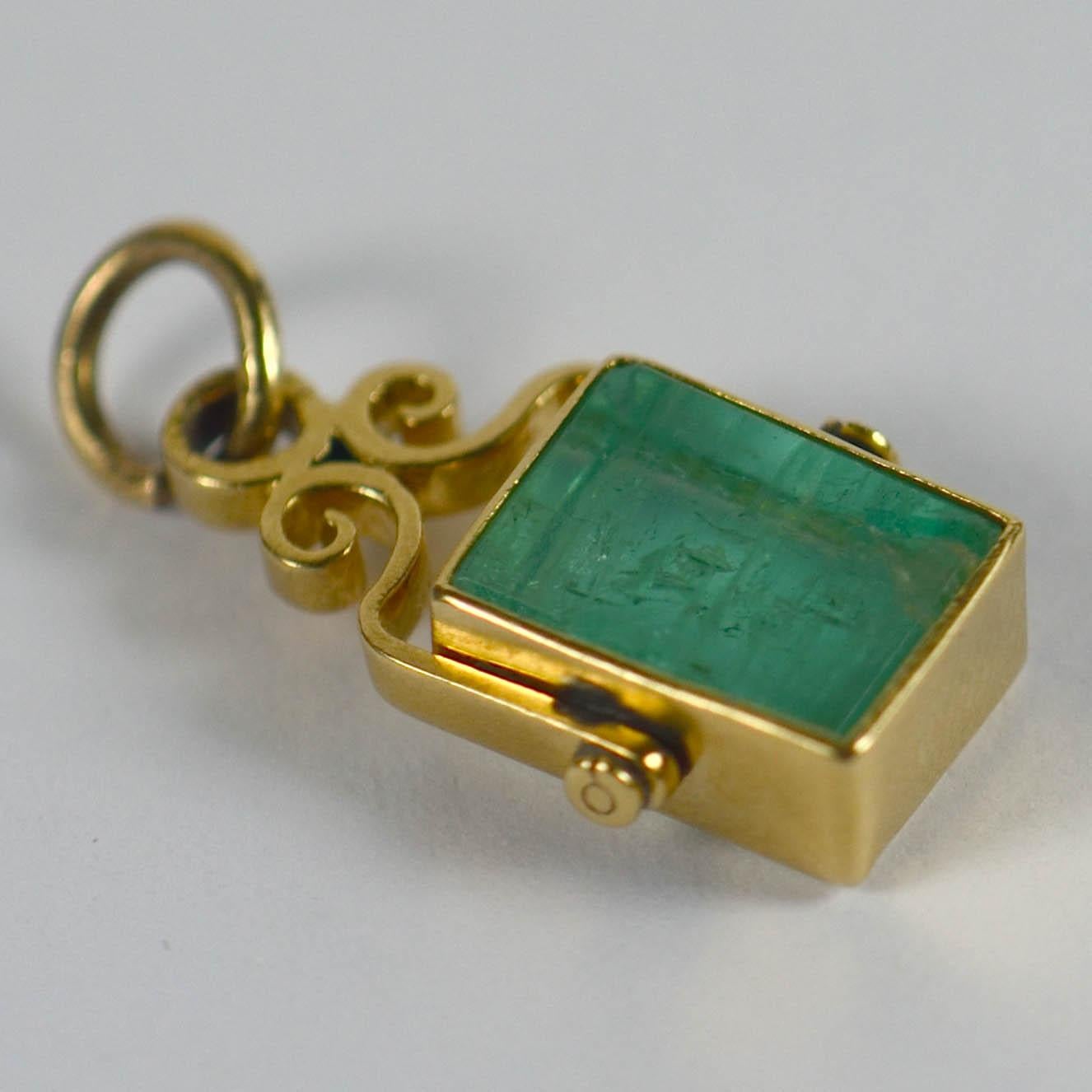 An unusual French charm composed of a rectangular polished slab of natural untreated emerald in a yellow gold frame with scroll mounts. The jardin of the emerald is on full display as light floods the back of this stone. 
Stamped with the eagle's