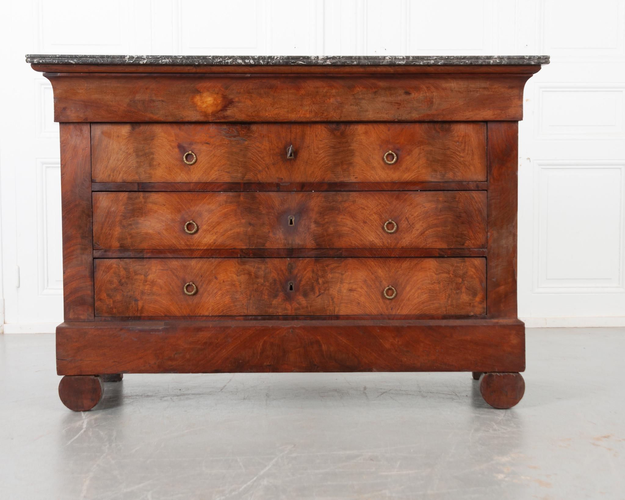 A fabulous French mahogany commode from 19th century France, circa 1840’s. The stunning gray and white marble top with rounded front corners is in good antique condition with few signs of wear. The apron houses a hidden drawer, free of hardware.