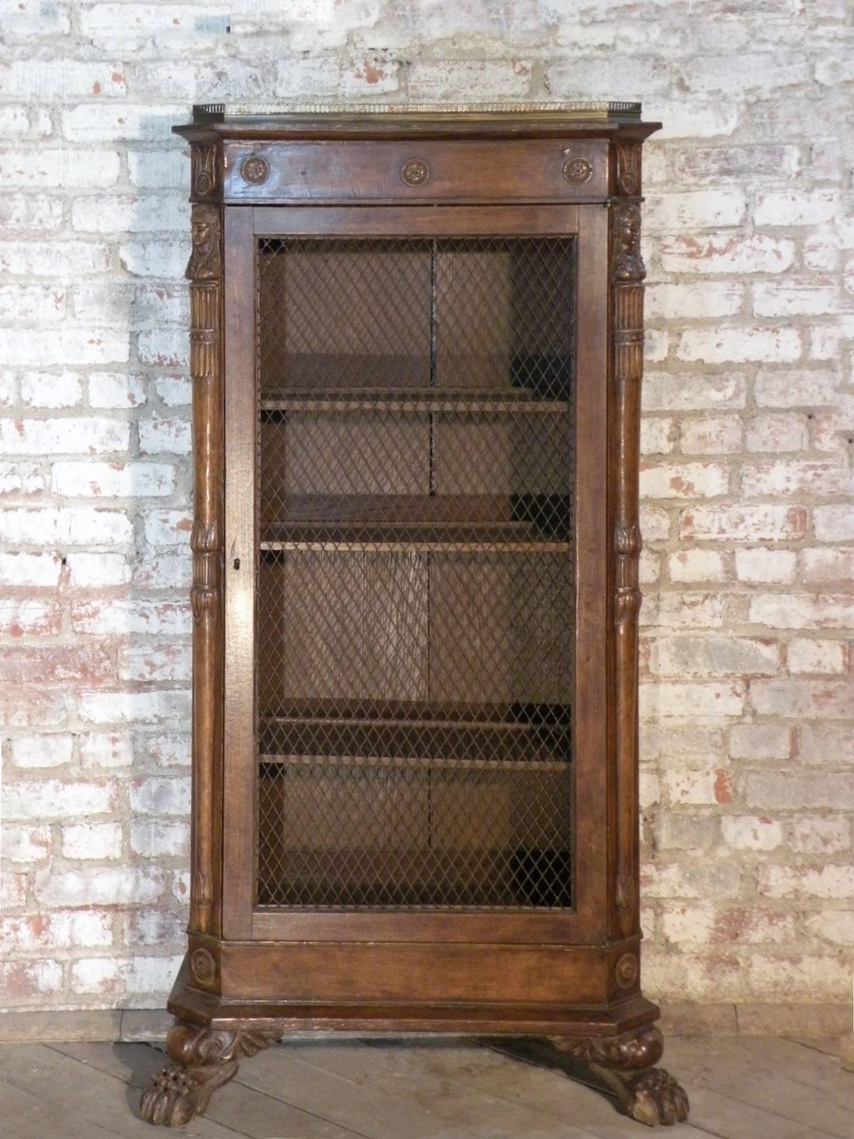 Small French Empire bookcase/cabinet with framed glazed sides, featuring a molded wooden elongated X on the inside, one wire-mesh-inset door, the corners embellished by sculpted columns topped by female busts, The top surmounted by an inset brass
