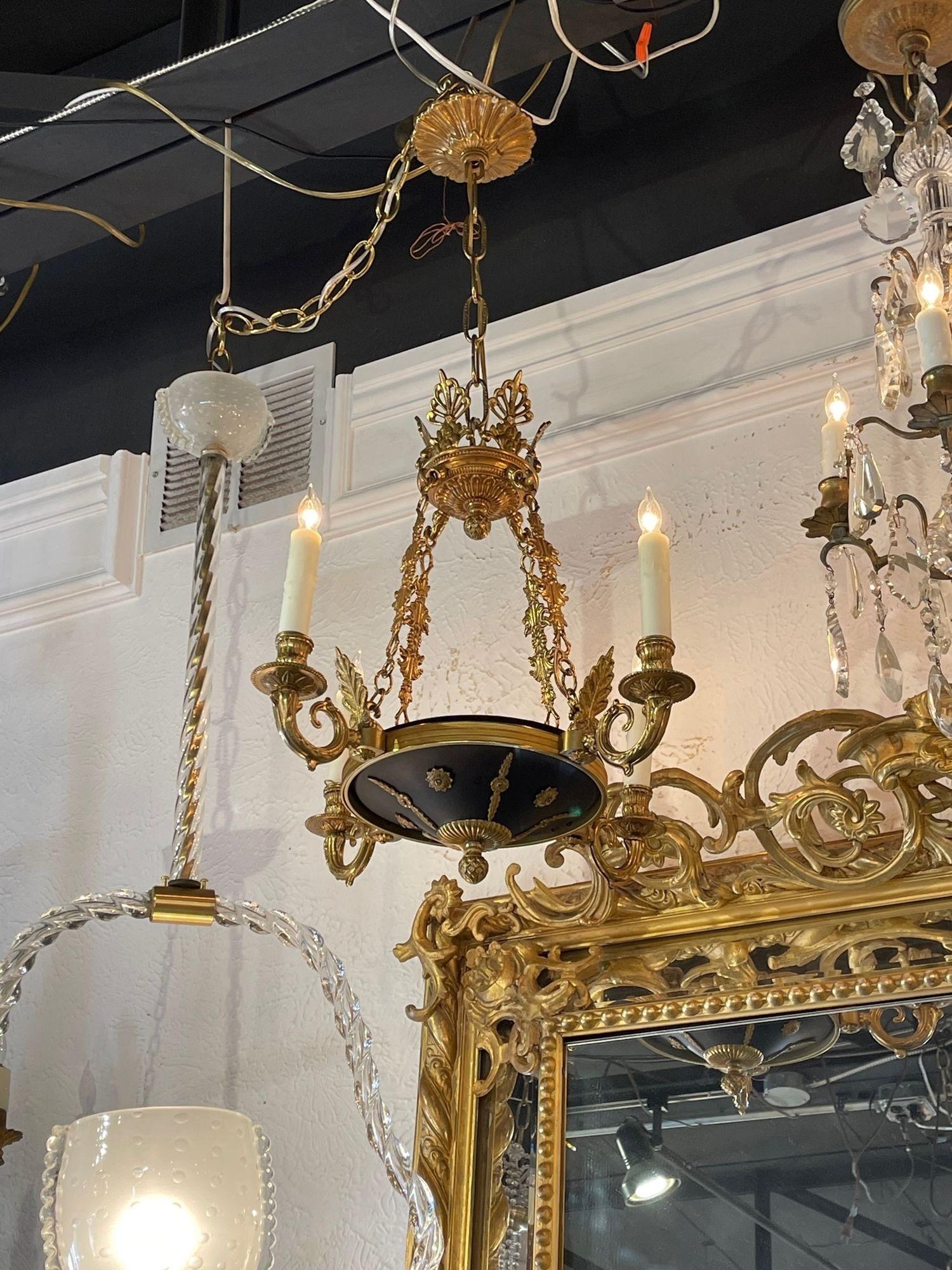 Petite French Empire 4-light bronze chandelier. Circa 1920. The chandelier has been professionally re-wired, cleaned and is ready to hang. Includes matching chain and canopy.