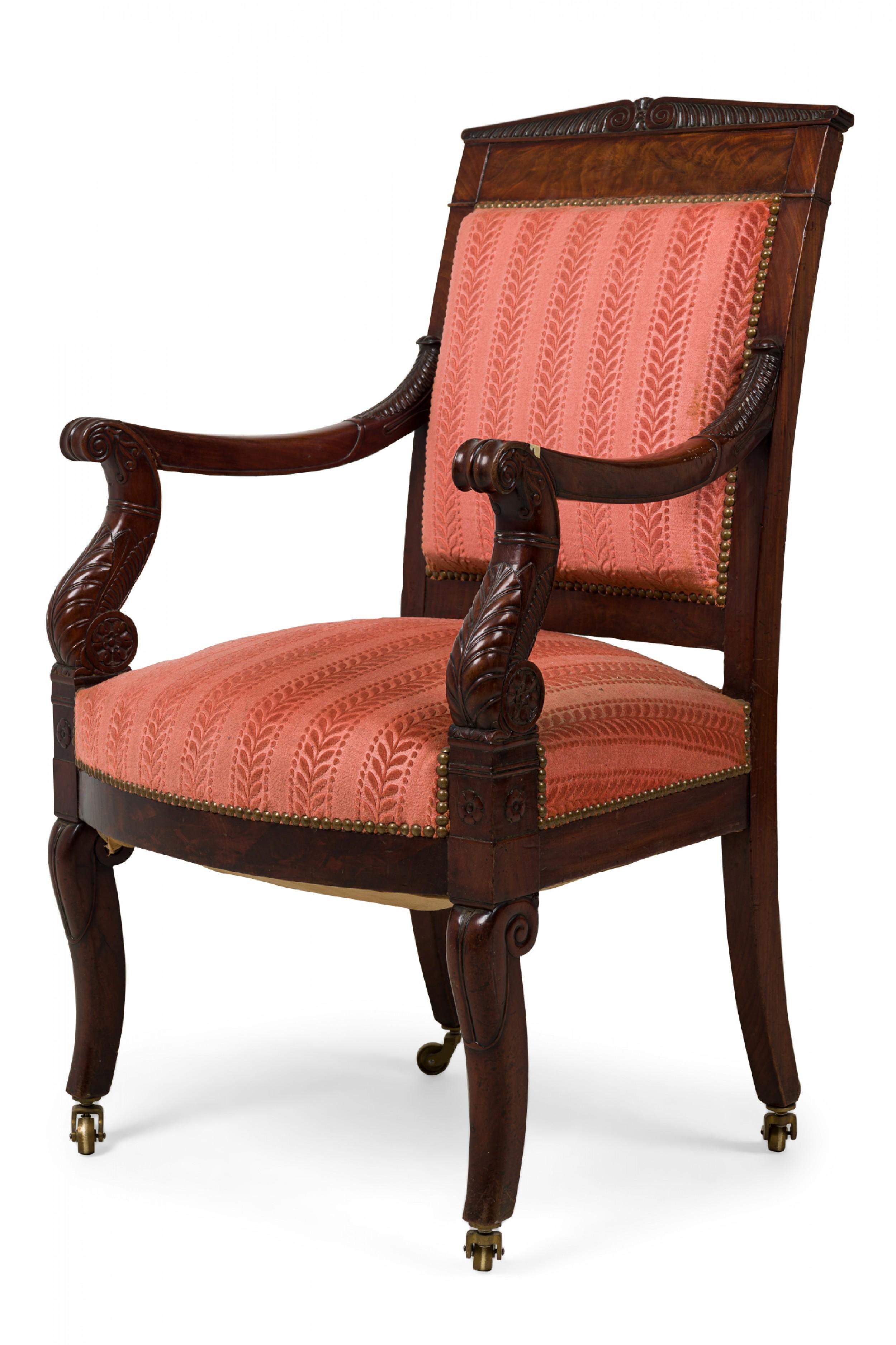 French Restoration mahogany armchair having a rectangular headrest topped by a tapering gadrooned crest, upturned scroll arms with acanthus embellishments, upholstered back and seat in a coral leaf-striped damask fabric with brass nailhead trim,