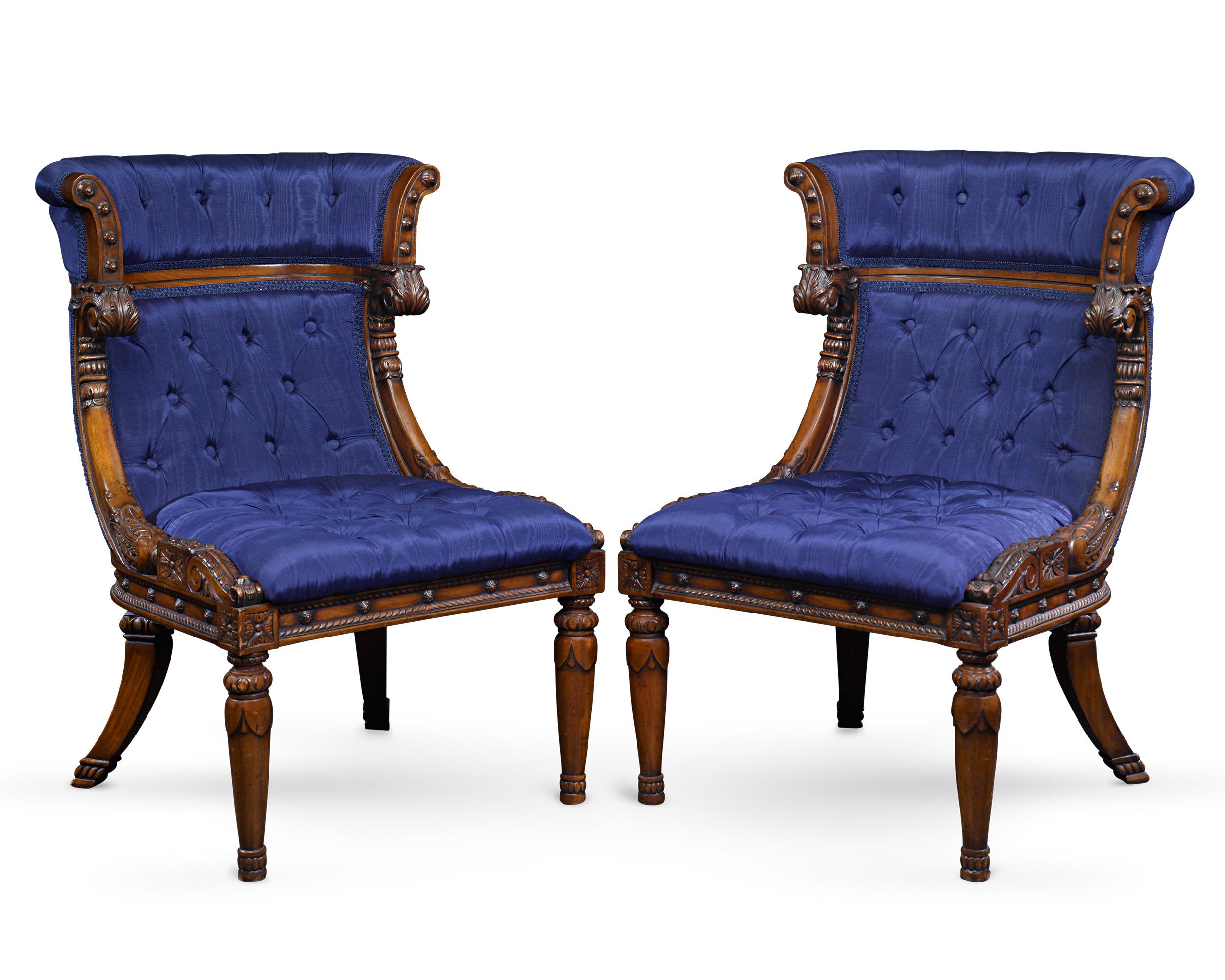 The beautiful design of this pair of French upholstered bergère chairs exemplifies the artistry and elegance of the Empire period. Exhibiting perfect proportions, the chairs are enhanced by royal blue upholstery and carved mahogany with symmetrical