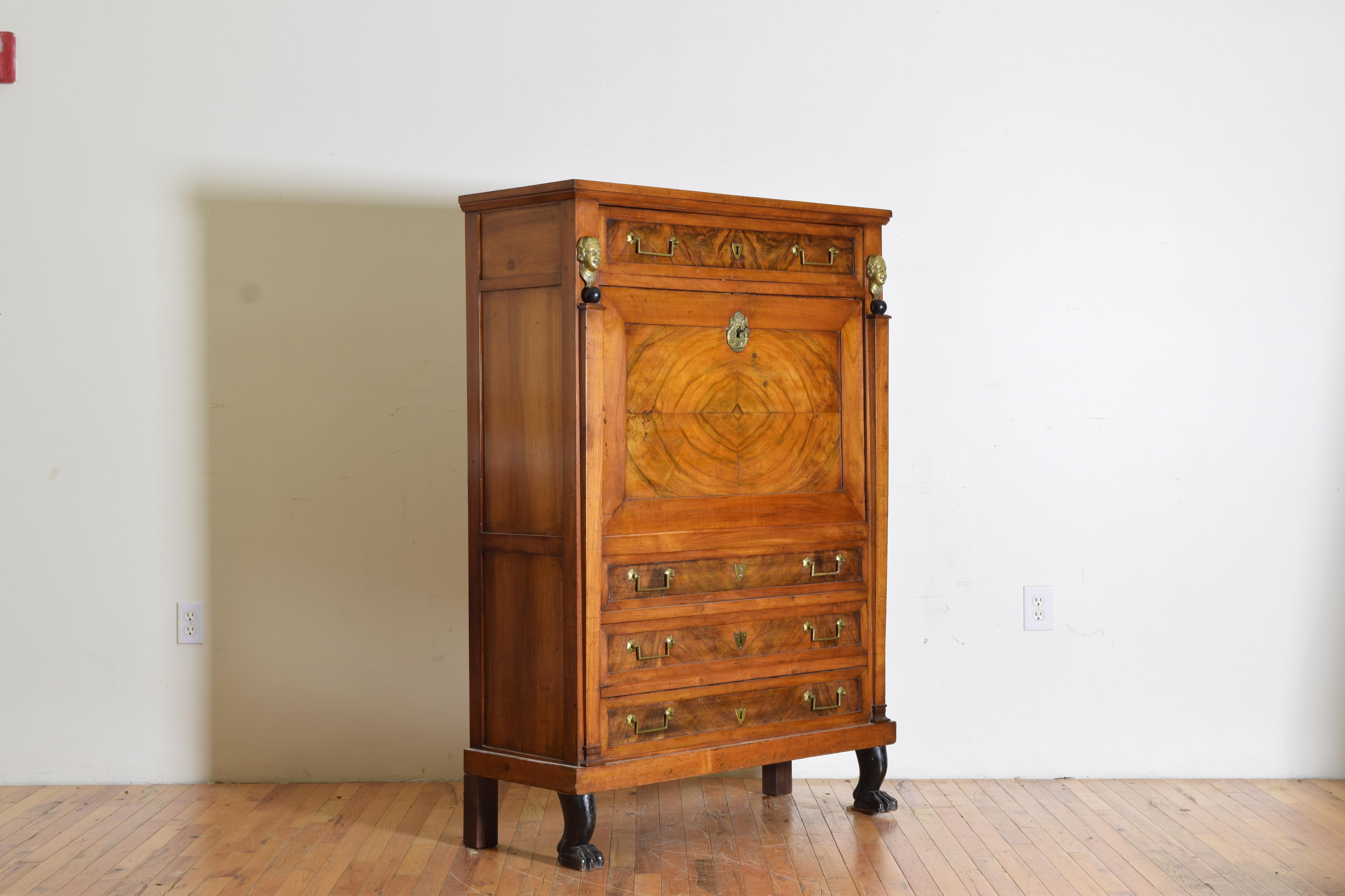 Having a rectangular top above a conforming case housing three drawers, one faux drawer, and a fall front desk with a leather writing surface and interior shelving and secret drawers, with stylized brass masks above ebonized balls, raised on
