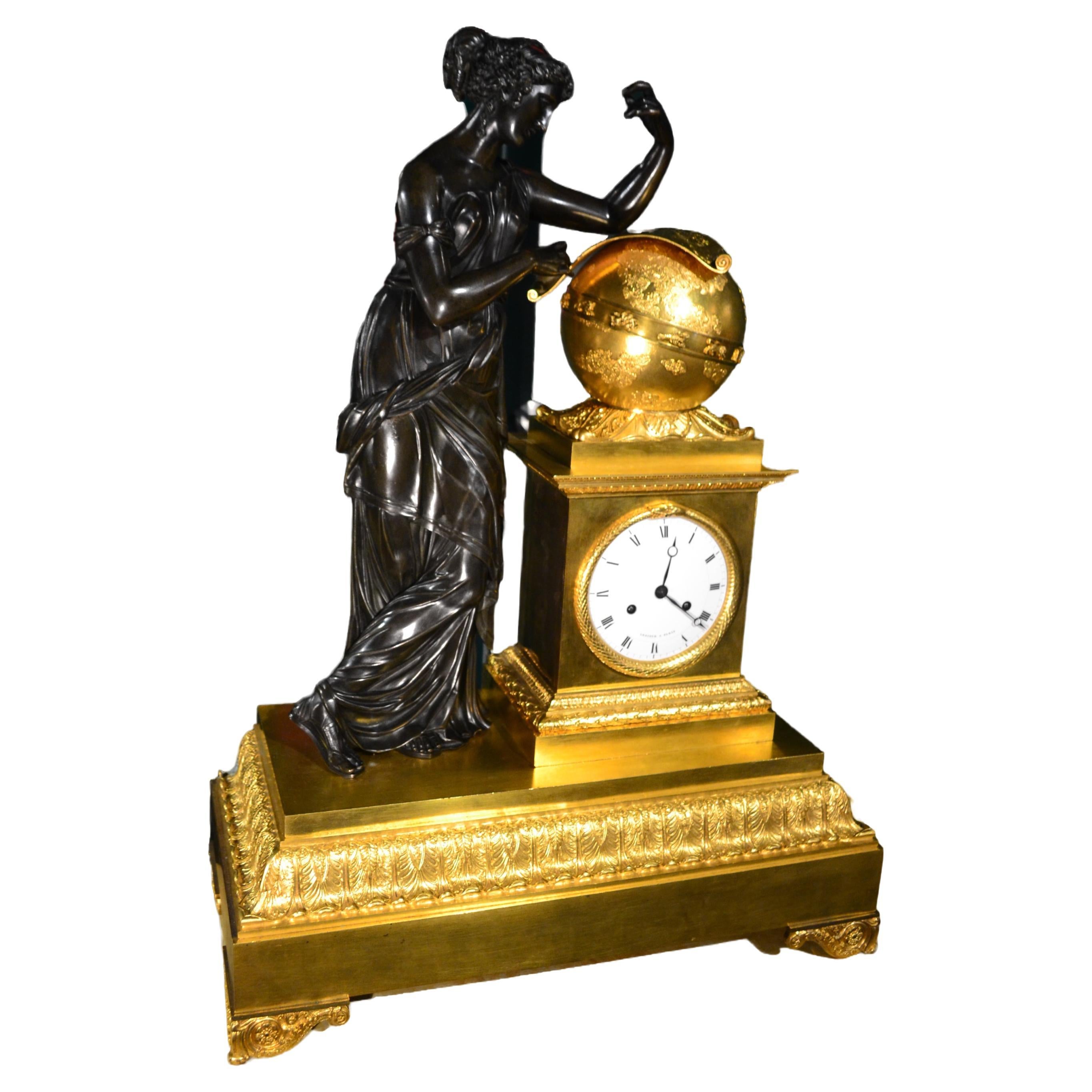 
A magnificent large gilded and patinated bronze period French Empire mantle clock depicting Urania the Greek Muse of Astronomy standing on a stepped rectangular gilded bronze base her left elbow resting on a large gilded globe of the heavens with a
